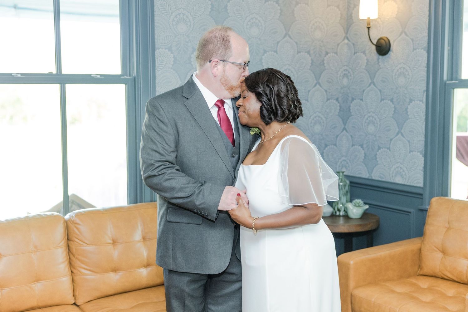 Wedding ceremony in an elegant indoor venue with soft lighting and wooden beams.