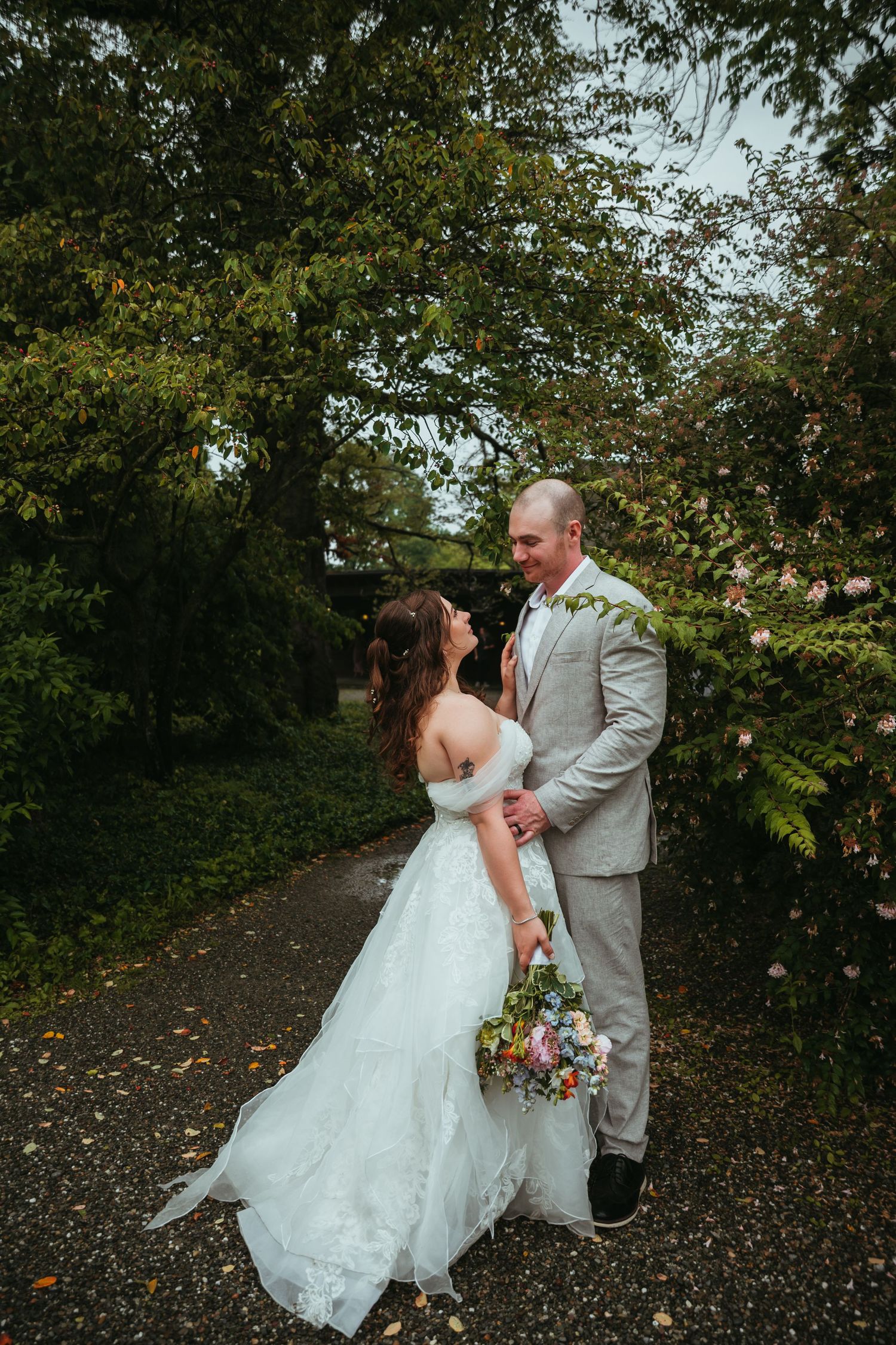 Newlyweds sharing playful moment on path surrounded by autumn trees.