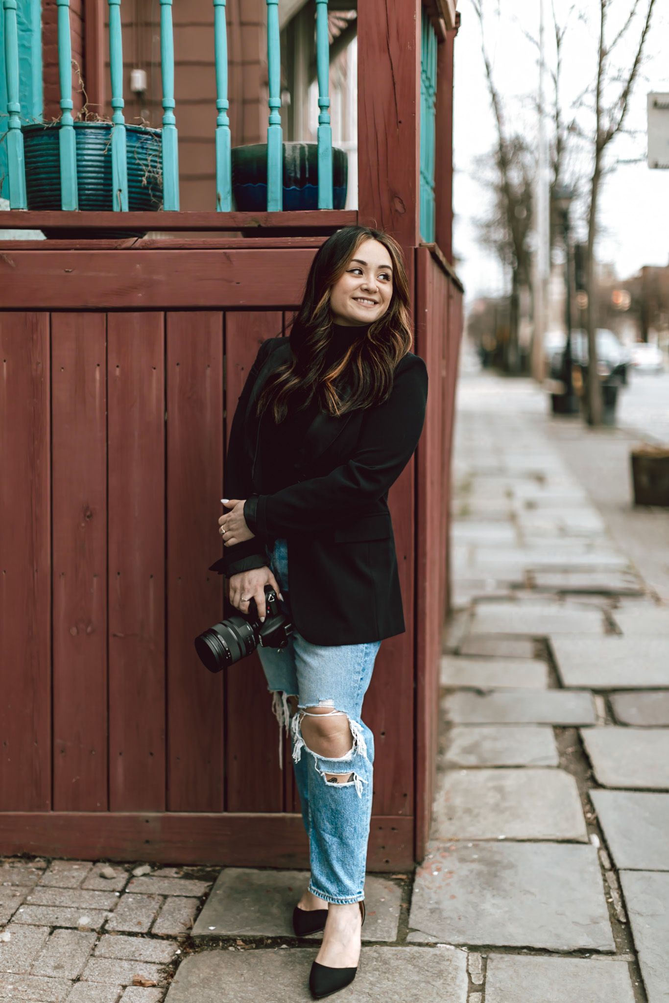 Series of playful poses by a turquoise and brown fence showing casual style and ripped jeans.