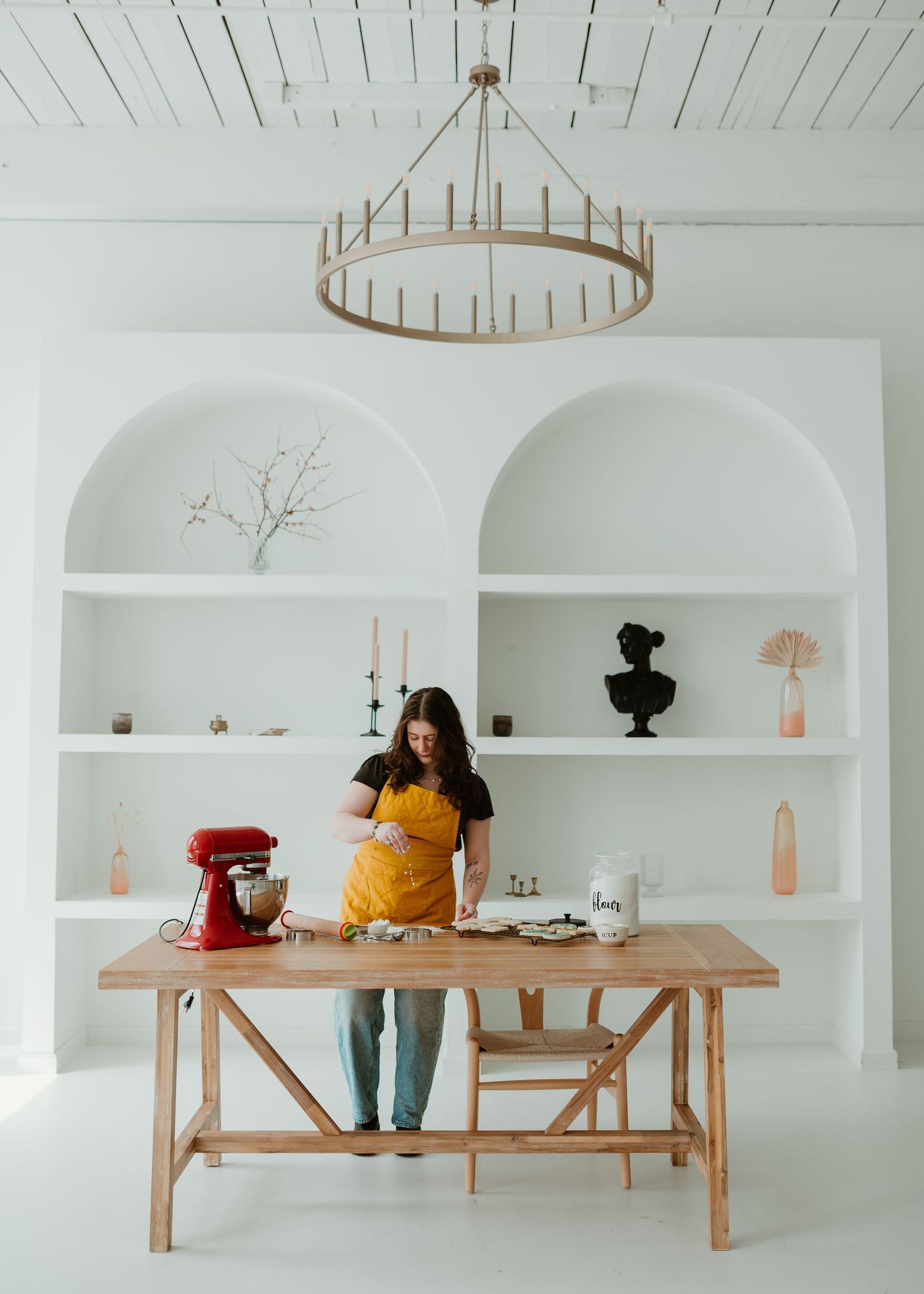 Minimalist white kitchen interior with wooden bench and built-in shelving.