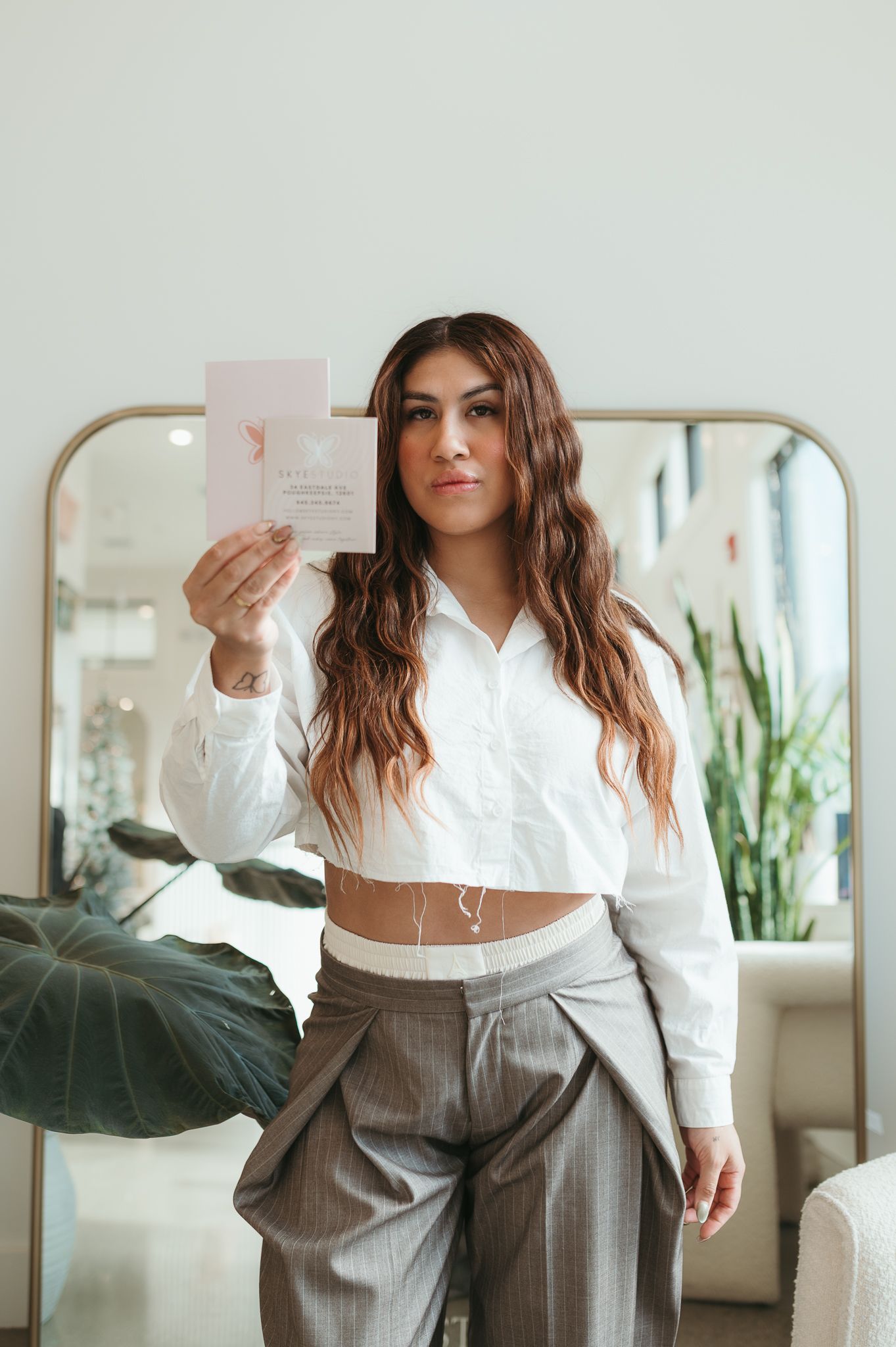 Professional business outfit featuring a white button-down crop top paired with high-waisted gray trousers.