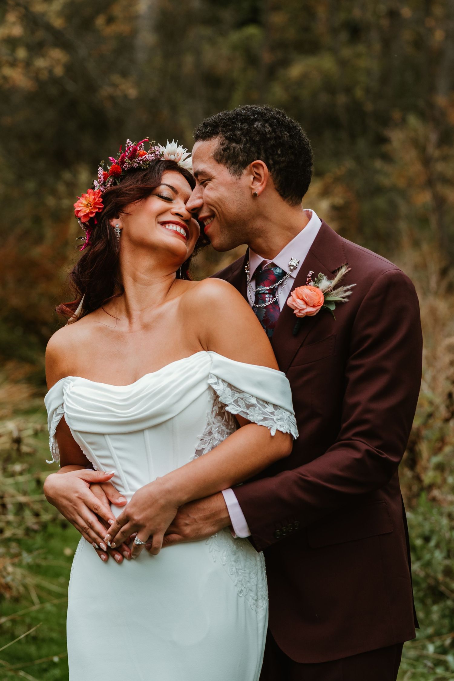 A romantic wedding couple embraces outdoors during an autumn photo session in a natural setting.