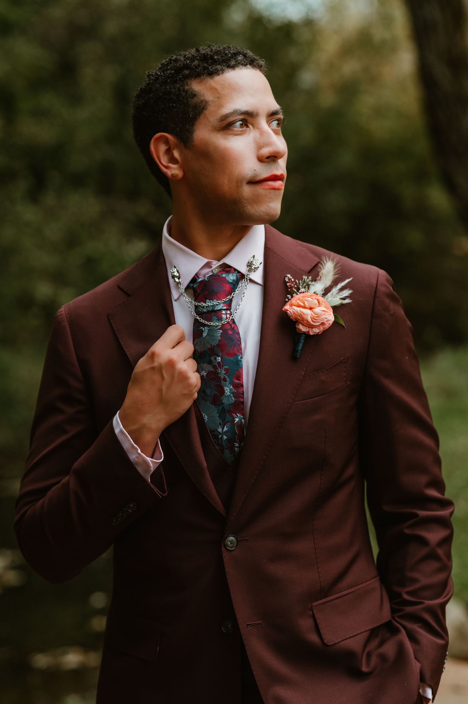 A groom in a burgundy suit and floral tie adjusts his collar while posing outdoors in a multi-panel photo sequence.