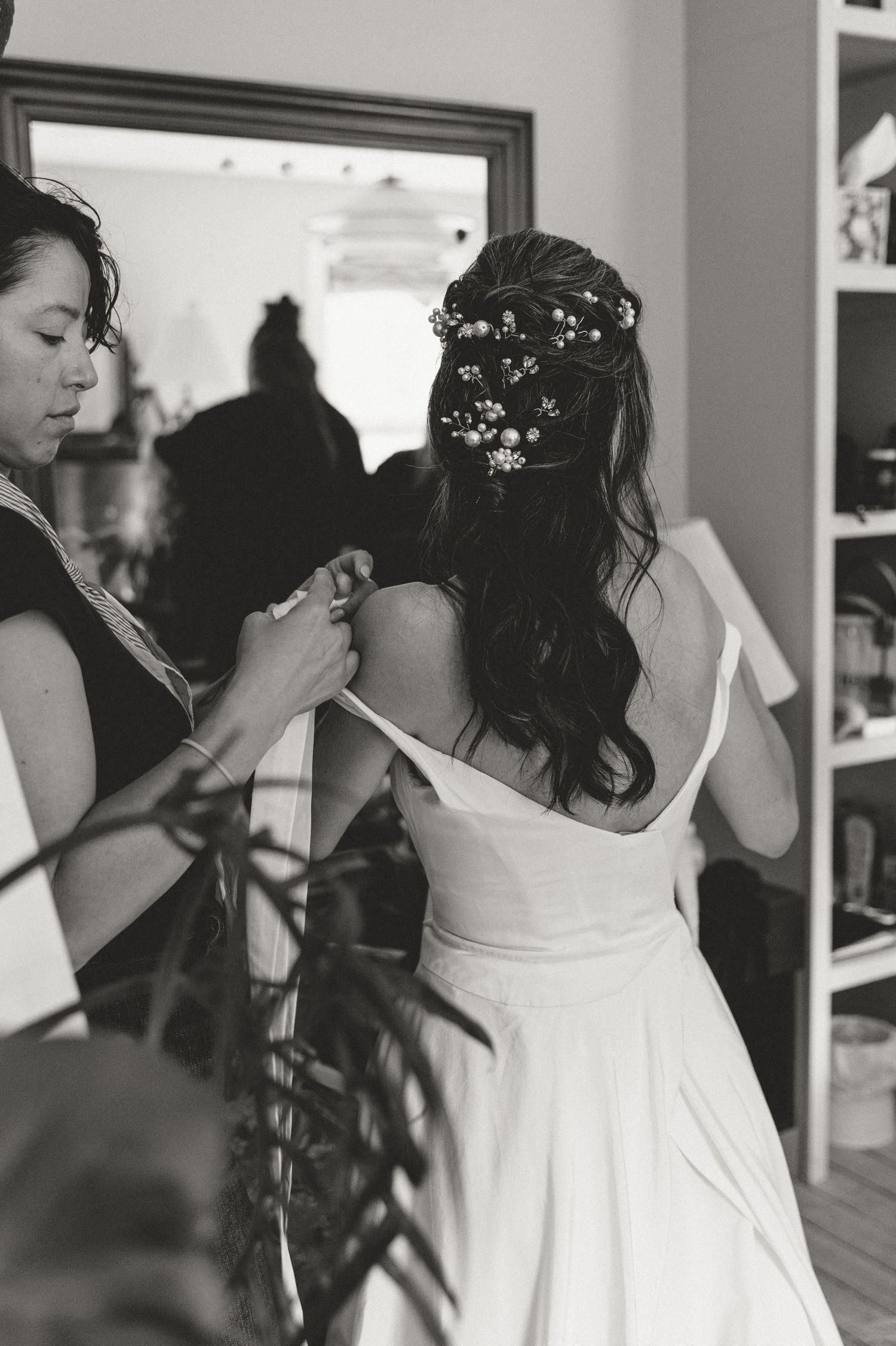 A series of black and white photos showing wedding preparation moments with a person in a white dress getting ready.