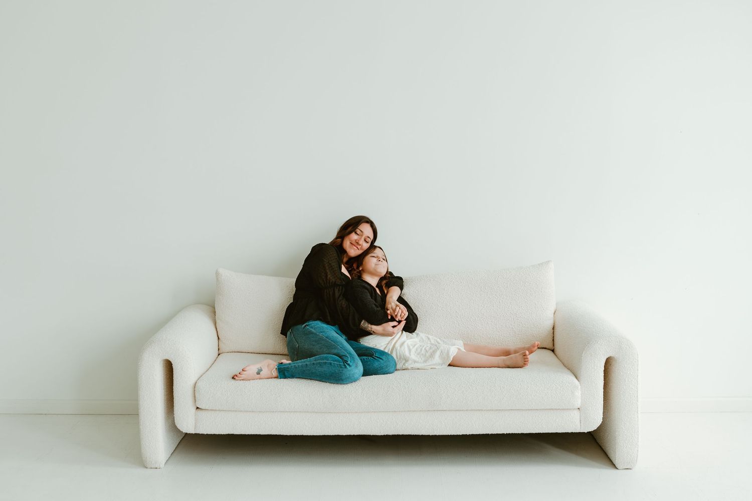 Minimalist portrait on white couch against white wall.