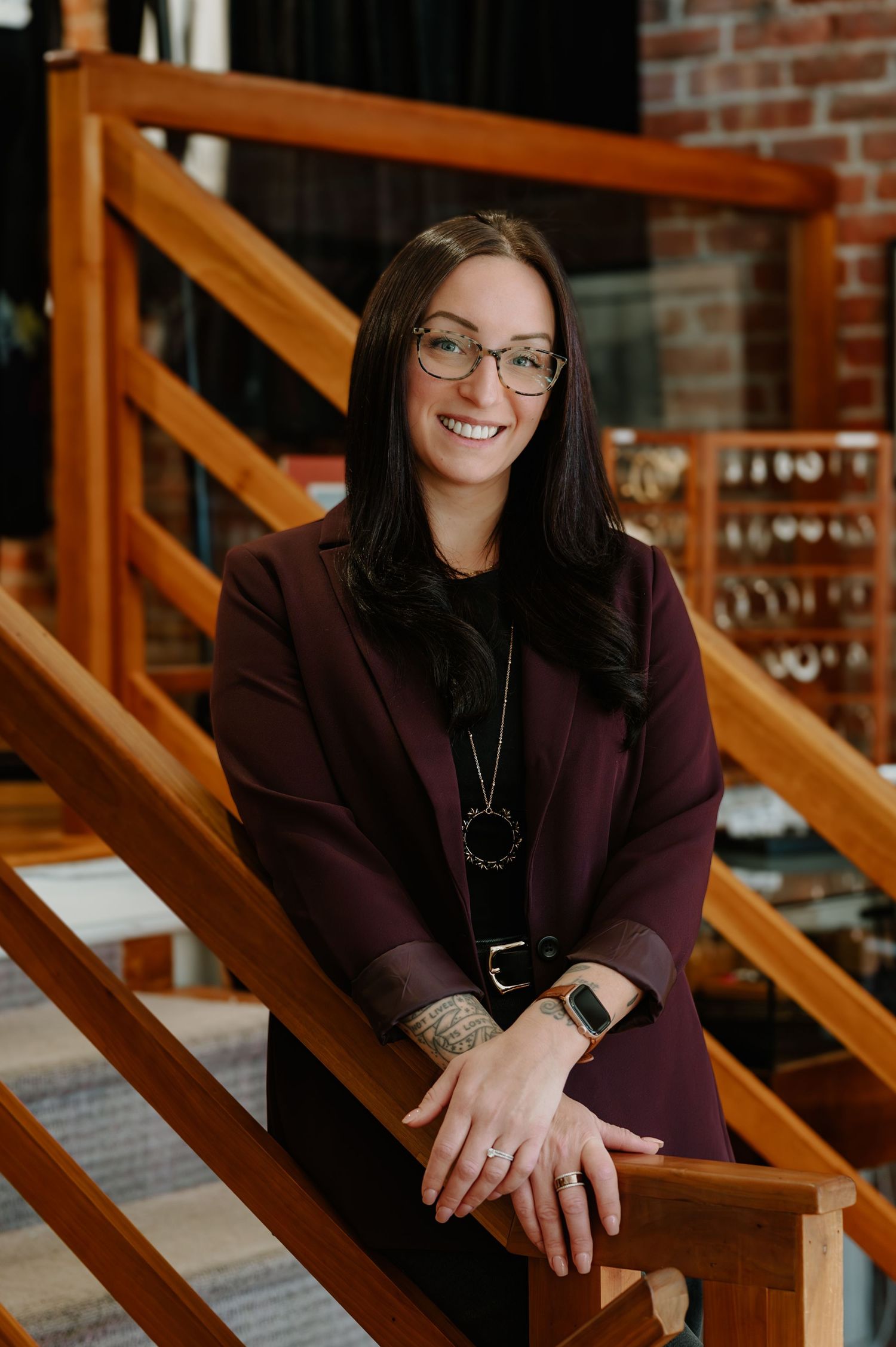 Professional portrait series showing person in burgundy blazer seated on wooden stairs with brick wall background.