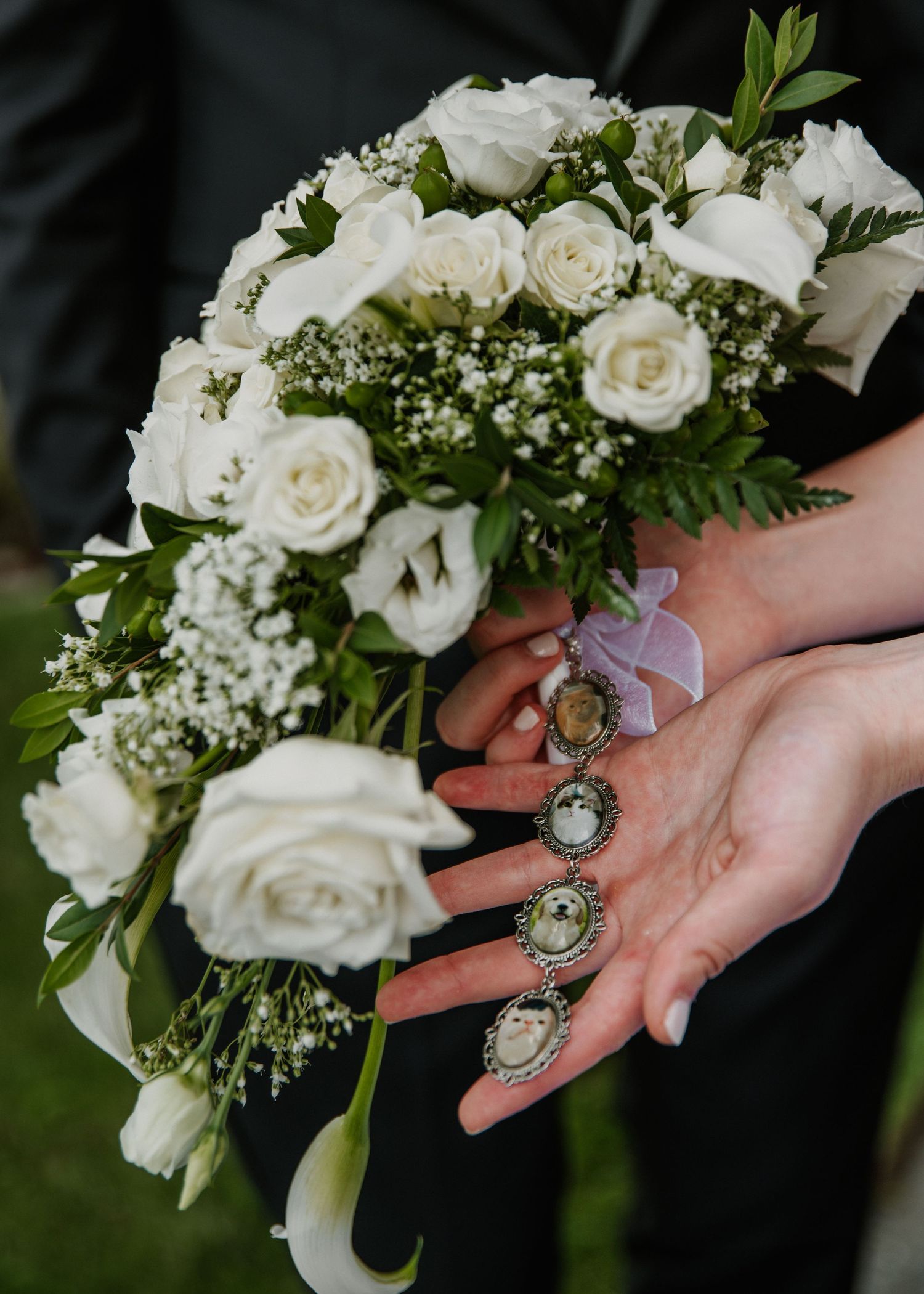 Bride holding white rose wedding bouquet with baby's breath while displaying vintage cameo memorial charms on her fingers.