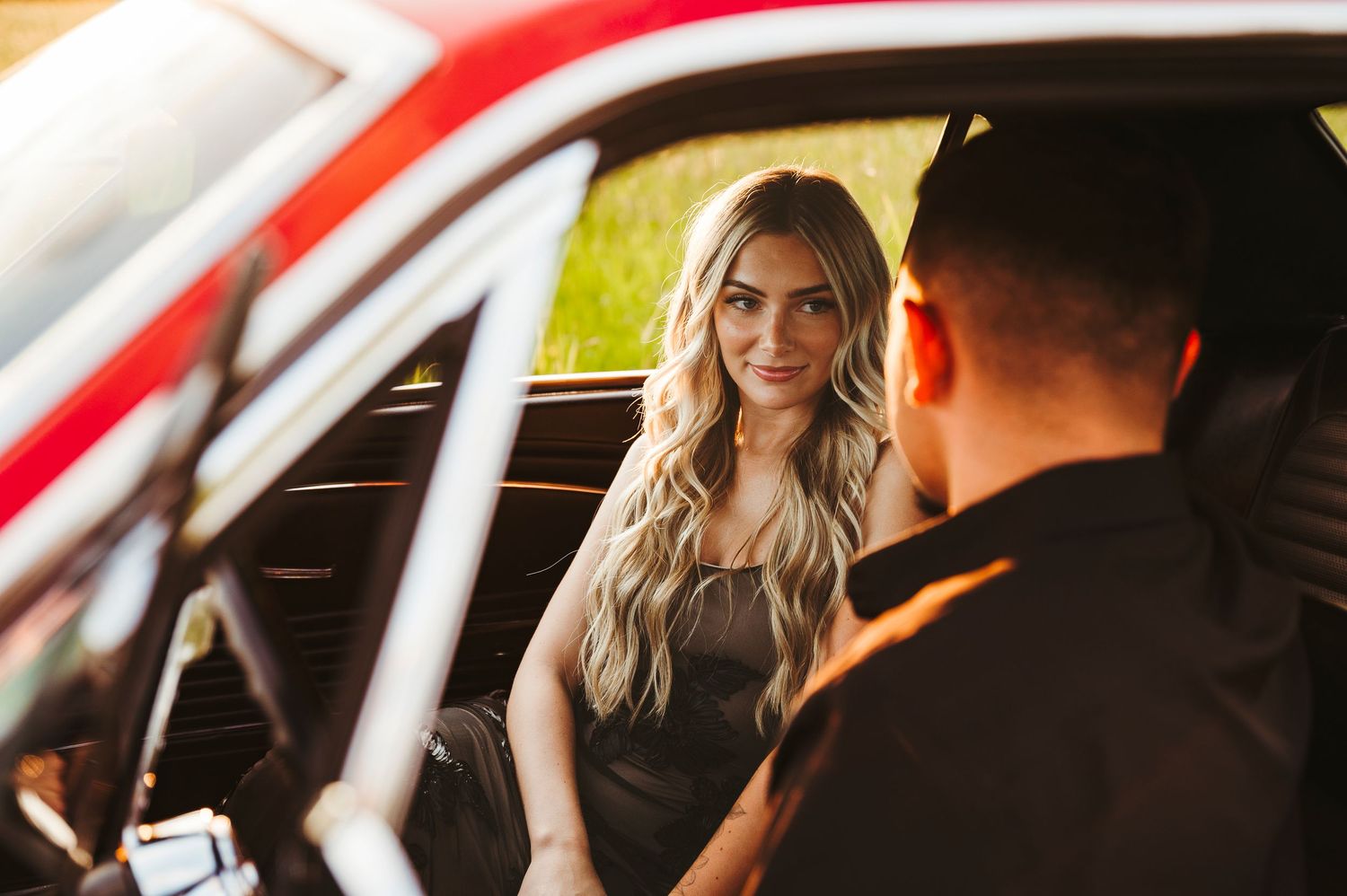 A romantic moment captured through a red car window at sunset.