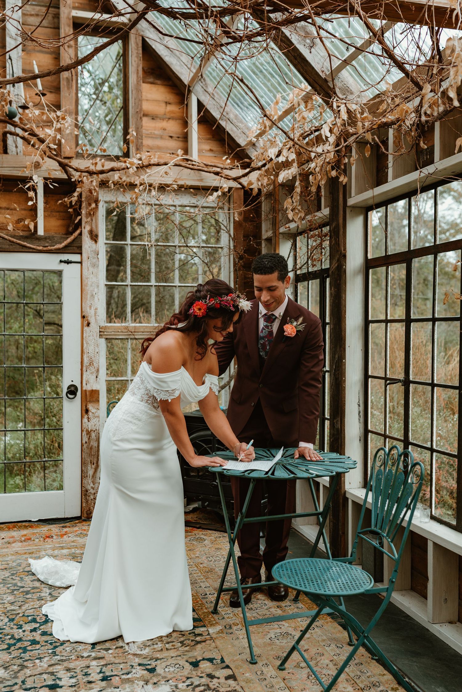 Romantic wedding scene inside a vintage greenhouse with antique furniture and glass windows creating a magical atmosphere.