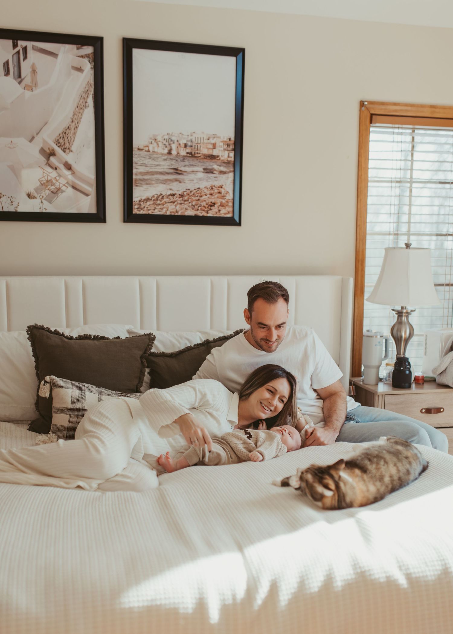 Cozy morning scene of family lounging in bright white bedroom with wall art.