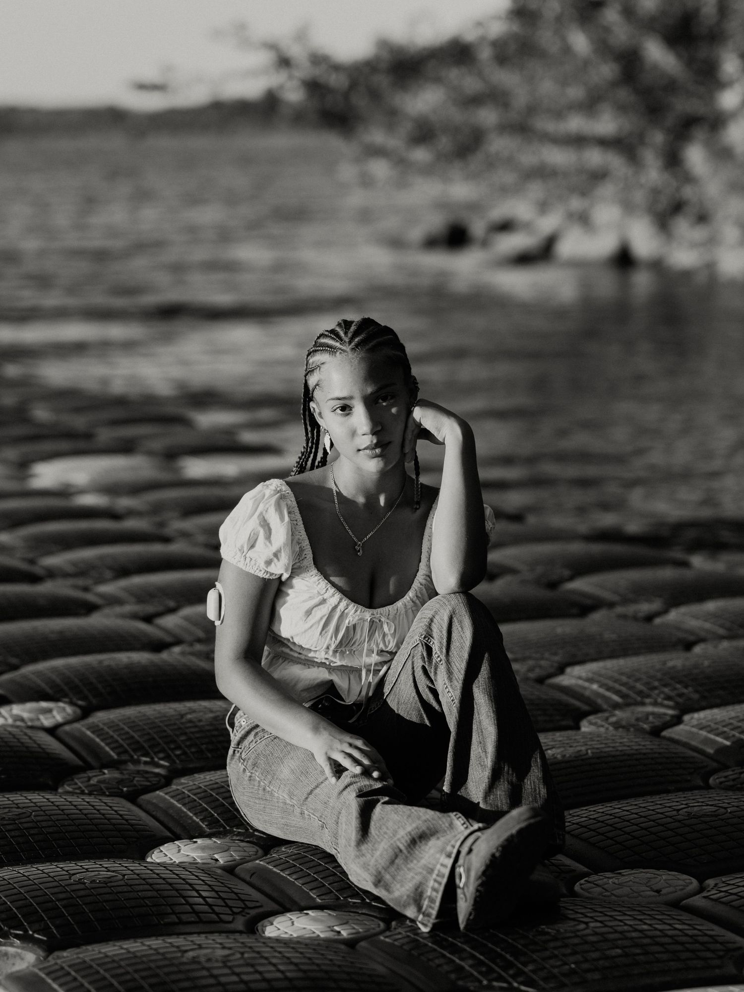 A person sits alone on rows of tires in dramatic black and white lighting creating a moody artistic composition.