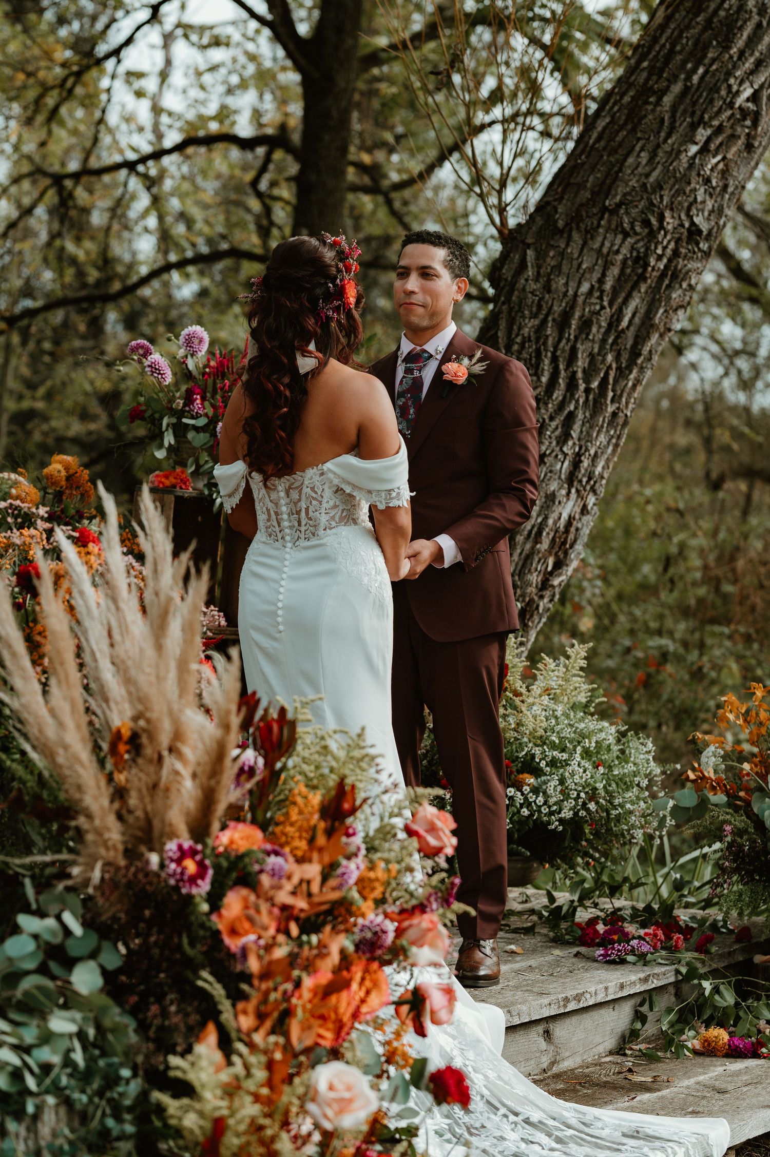 An outdoor wedding ceremony setup with vibrant autumn flowers and pampas grass decorations.