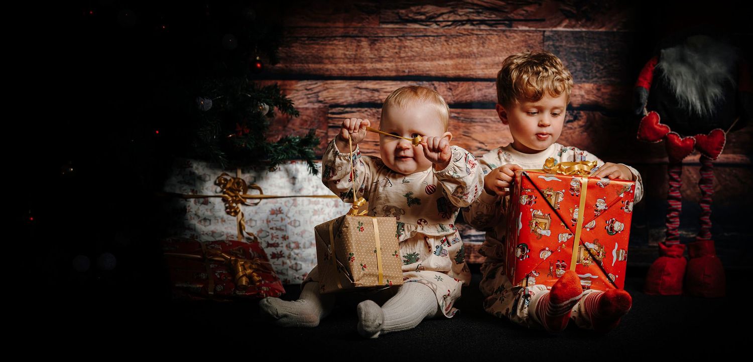 To børn leger med julegaver under en hyggelig julefotografering i Aalborg.