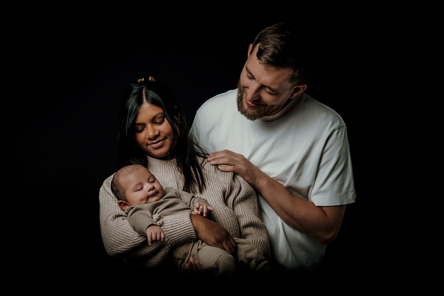 Fotograf Aalborg og Nordjylland er også familiefotograf og har taget et billede af forældre, der holder deres lille nyfødte.