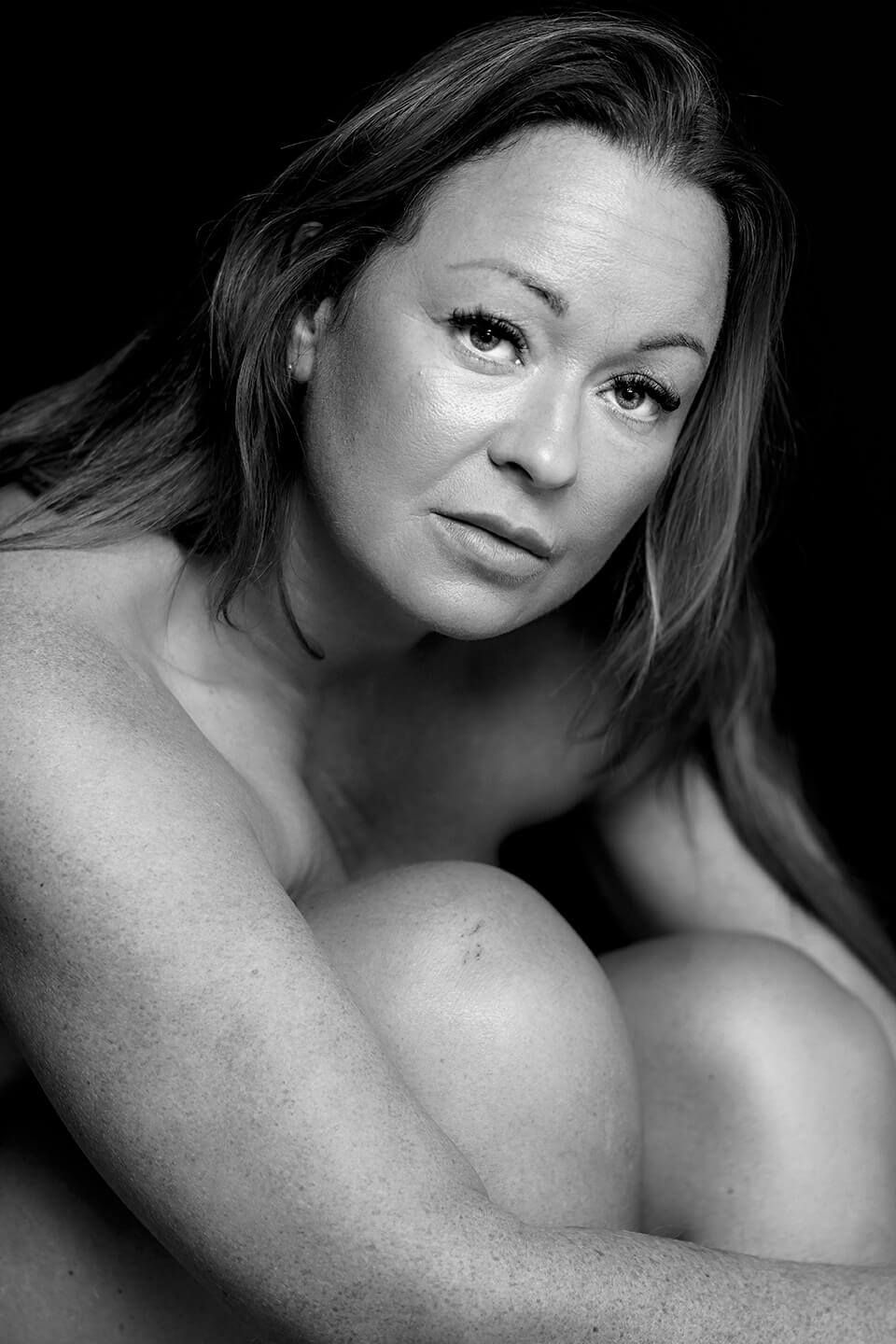Portræt i sort-hvid af kvinde der ser frem mod kameraet med følsomt og stærkt blik, af boudoirfotograf i Aalborg.