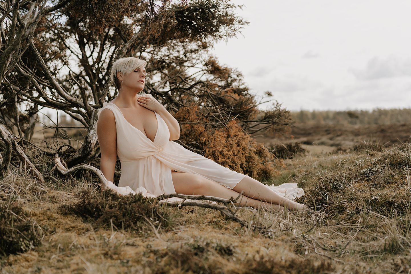 Elegant kvinde med kort hår ser op mod lyset omgivet af grene – fotograf Aalborg portræt.