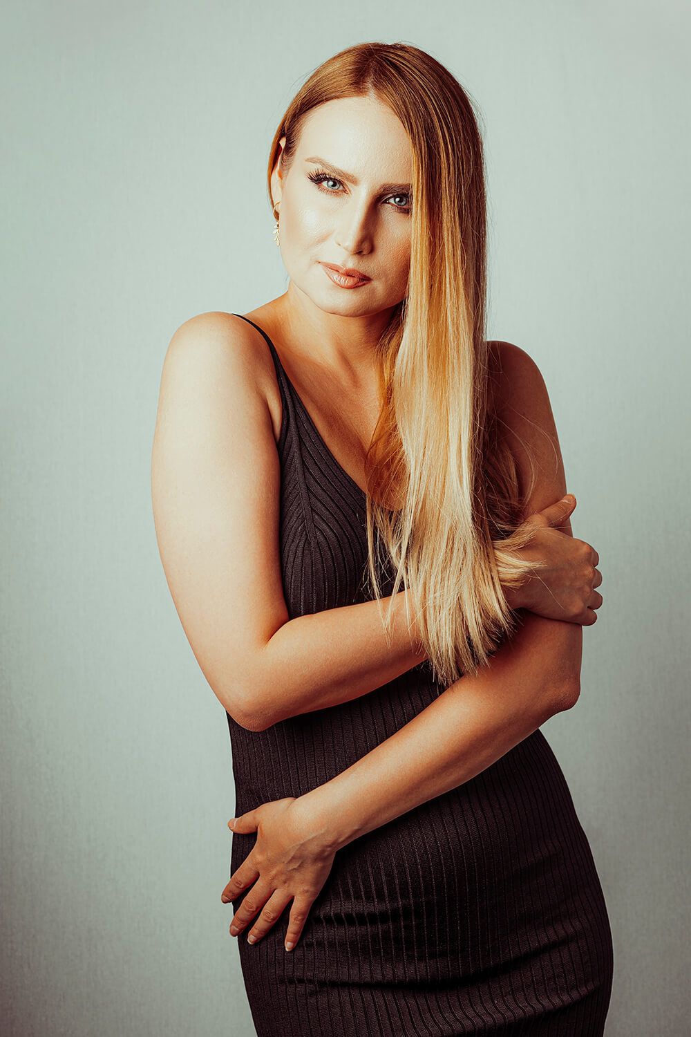 Kvinde i sort kjole – modelfoto med stærk eye-contact og simpel baggrund.