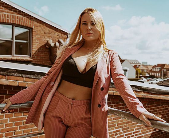 Portræt af kvinde i rosa jakkesæt på tagterrasse i Aalborg – moderne modelfotografi.