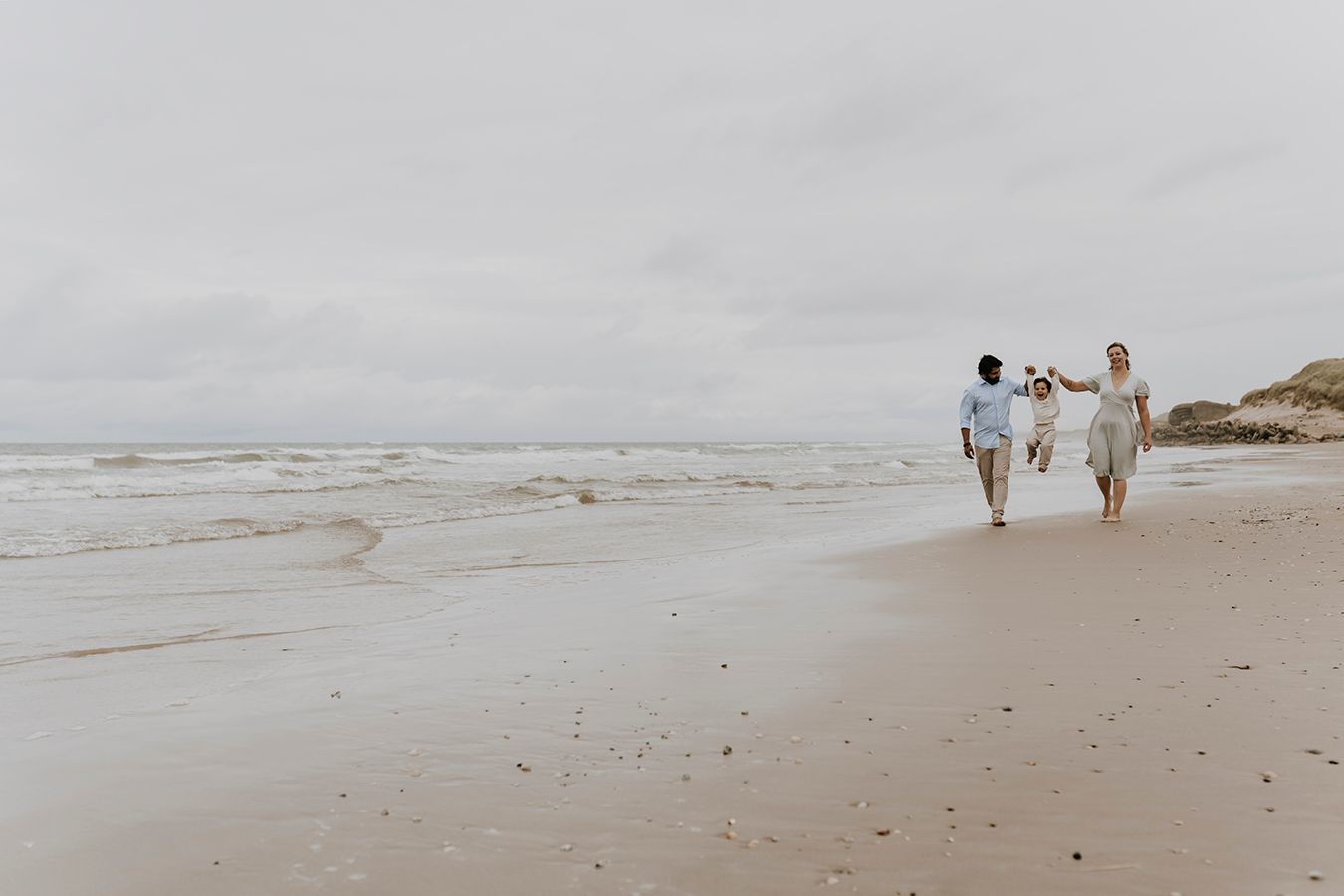 Familie går langs stranden med deres barn – naturlig familiefotografering ved havet nær Aalborg, JOEhansenFOTO.