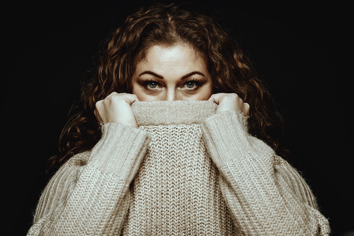 Modelfotograf Aalborg - Portræt af en kvinde der gemmer lidt af sit ansigt i en sweater, taget af fotograf i Aalborg, JOEhansenFOTO.