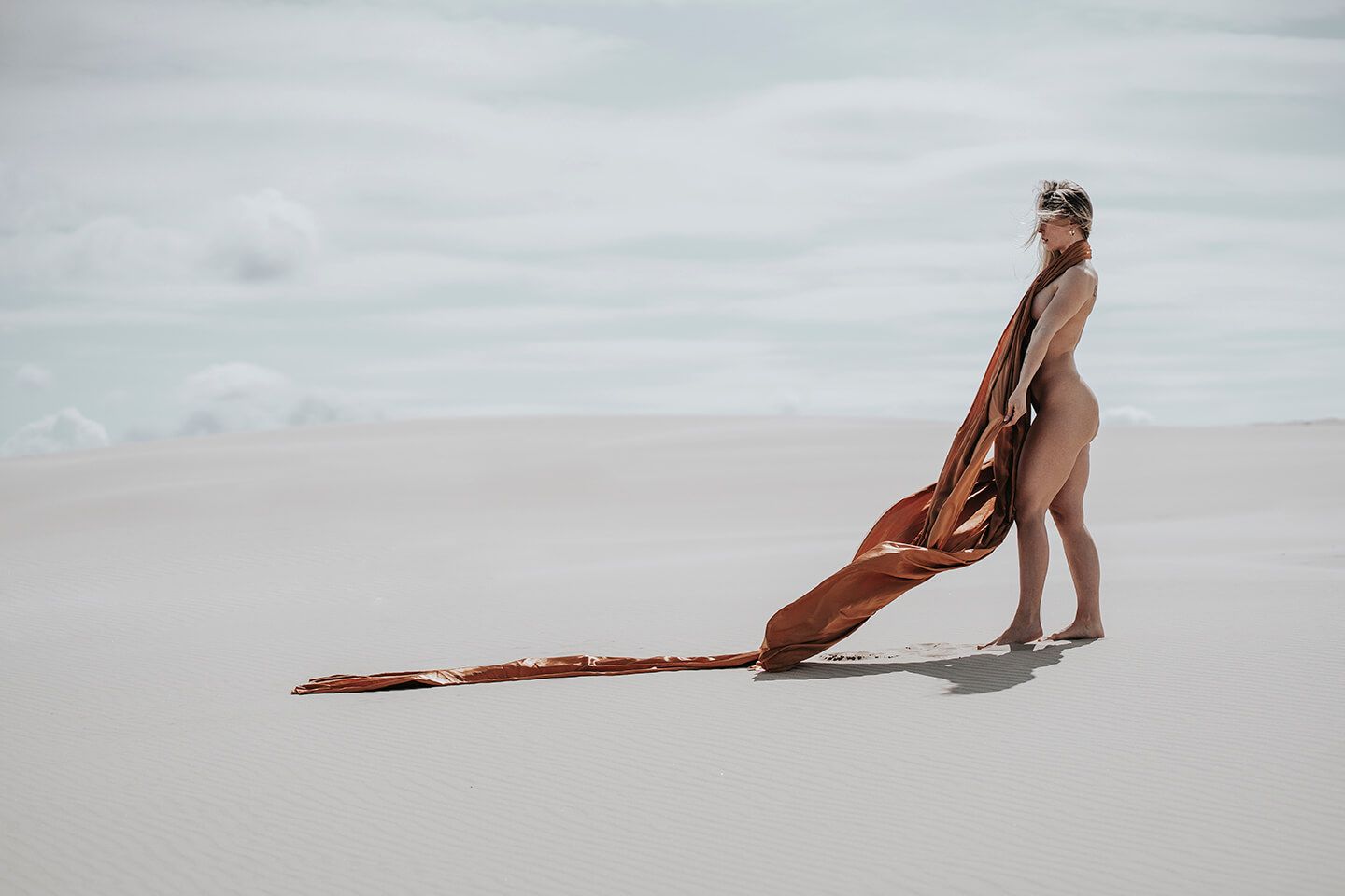 Fotograf i Aalborg sammen med kvindelig model i Råbjerg Mile, fotograferet, kun iført bronzefarvet stof.