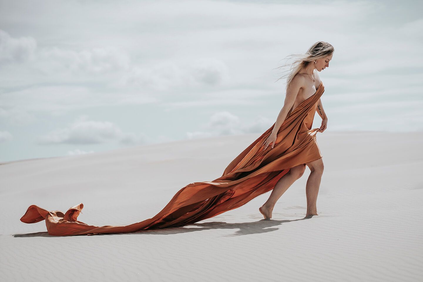 Fotograf i Aalborg sammen med kvindelig model i Råbjerg Mile, fotograferet, kun iført bronzefarvet stof.