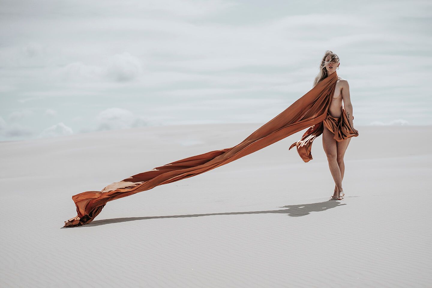 Fotograf i Aalborg sammen med kvindelig model i Råbjerg Mile, fotograferet, kun iført bronzefarvet stof.