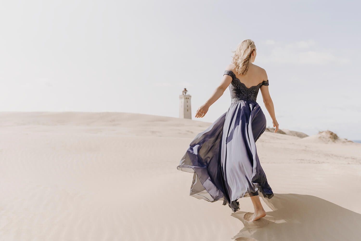 Kvinde i lilla kjole går barfodet gennem klitterne mod Rubjerg Knude – modelfotograf i Nordjylland.