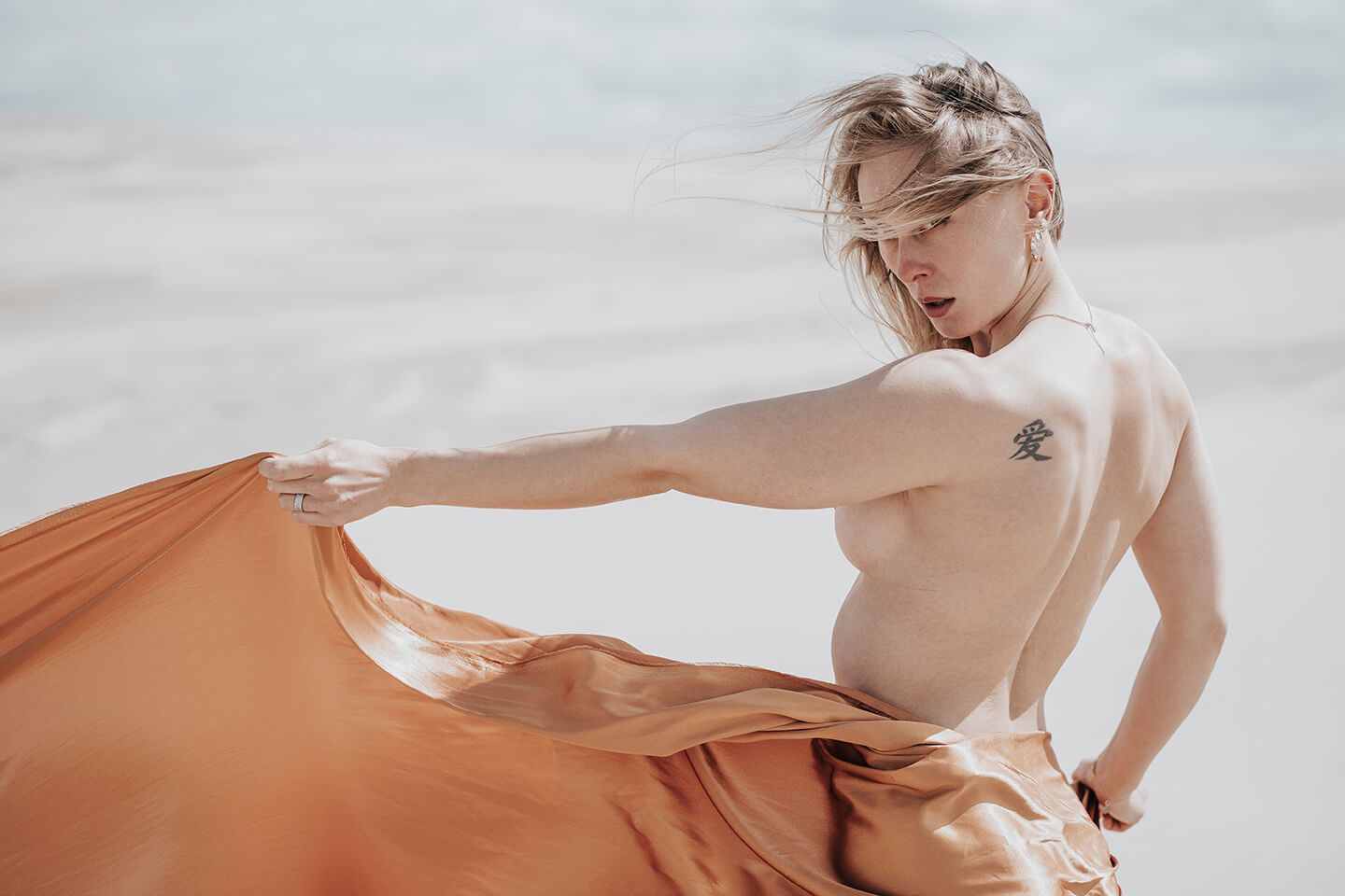 Fotograf i Aalborg sammen med kvindelig model i Råbjerg Mile, fotograferet, kun iført bronzefarvet stof.