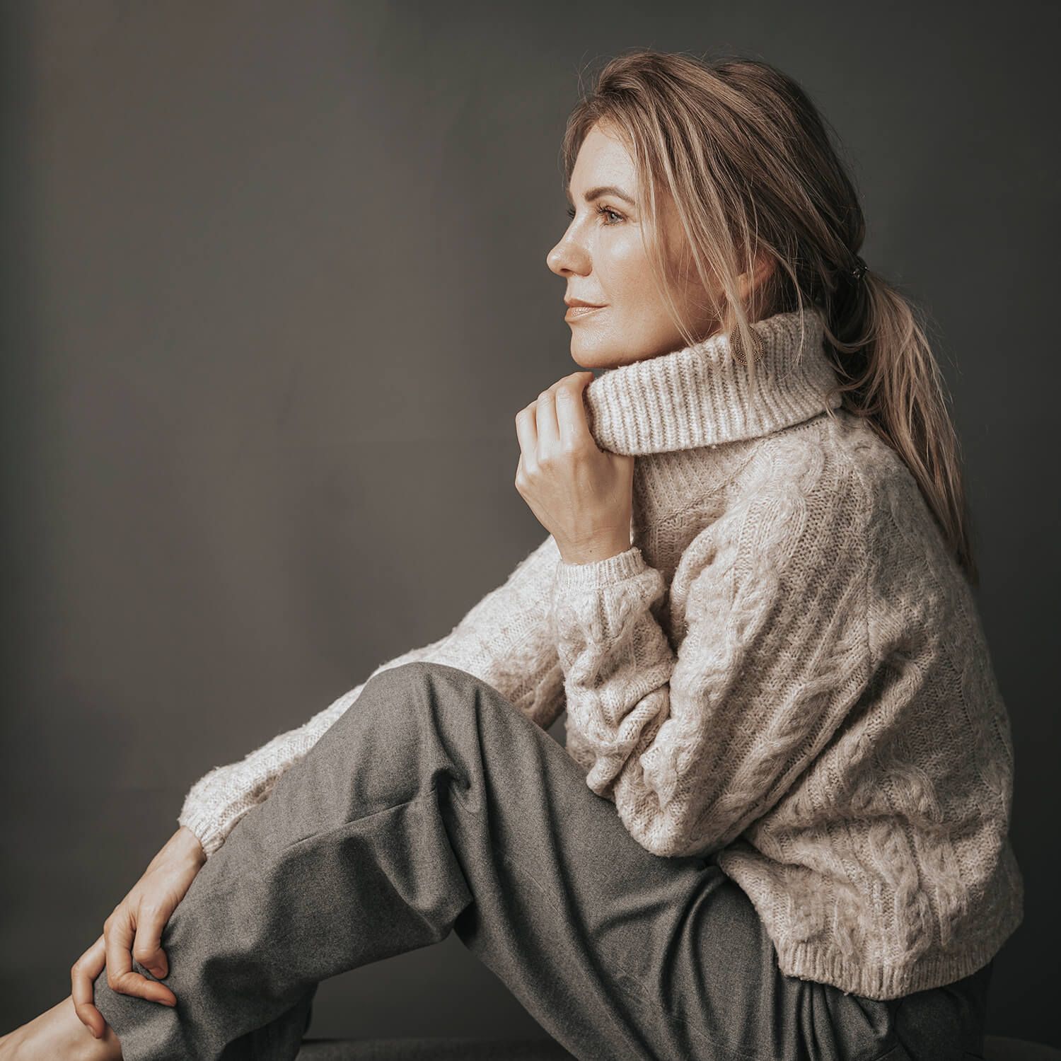 Modelfotografi i Aalborg med rolig stemning – Sandra Stahrenberg i striktrøje med blødt udtryk og lukkede øjne.