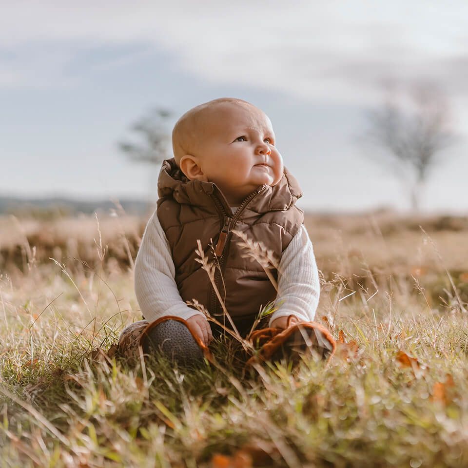 Børnefoto af baby udendørs taget af fotograf i Aars med naturlige farver og rolig stemning.