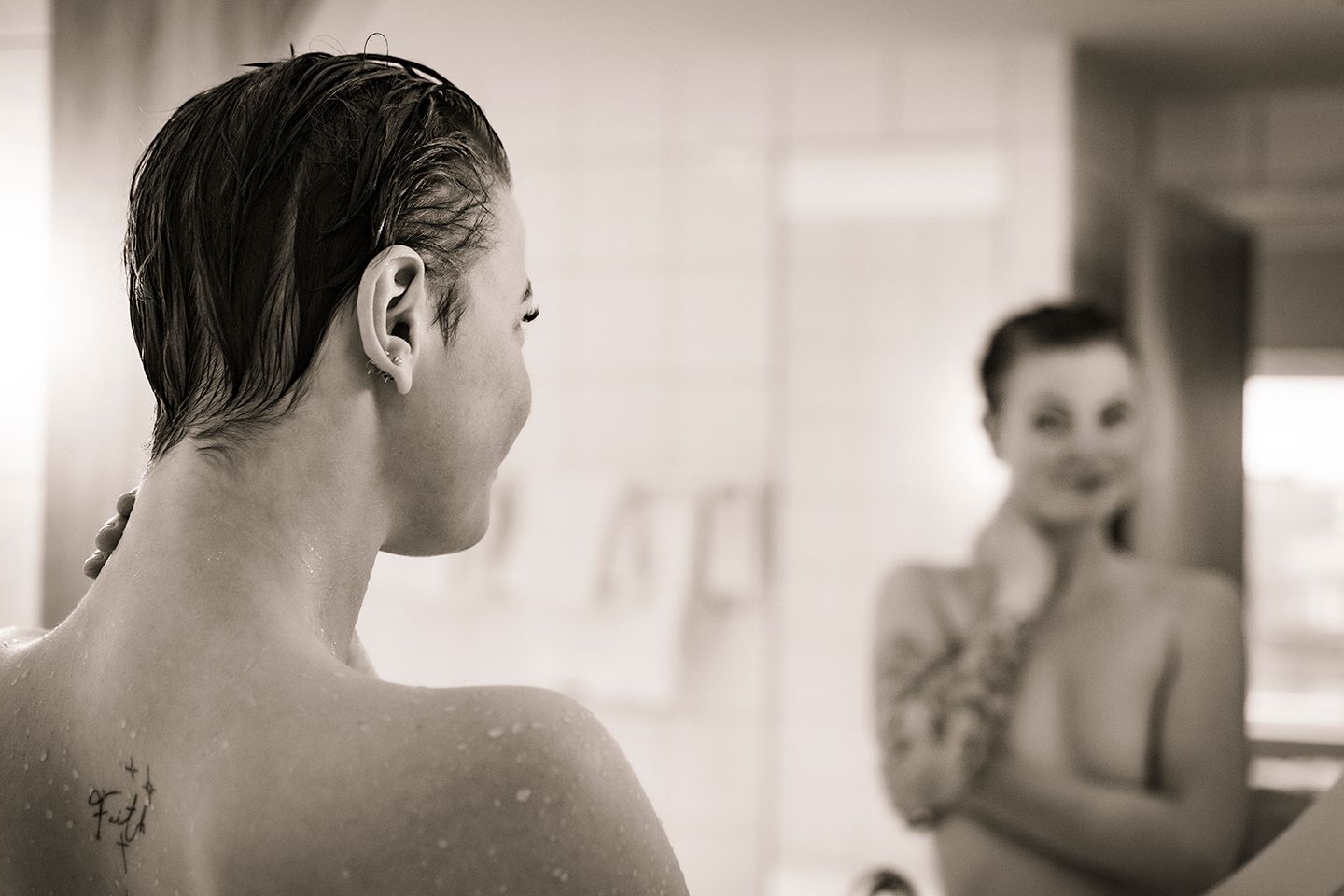 Kvinde foran spejl under en boudoirfotografering, hvor fokus er på kropsbevidsthed, ro og tryghed i processen.