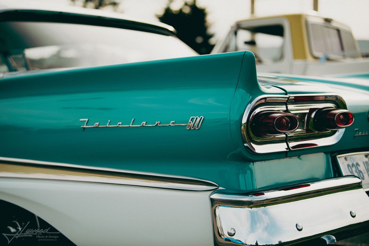 Close-up view of a turquoise vintage car's tail fin and chrome trim details.