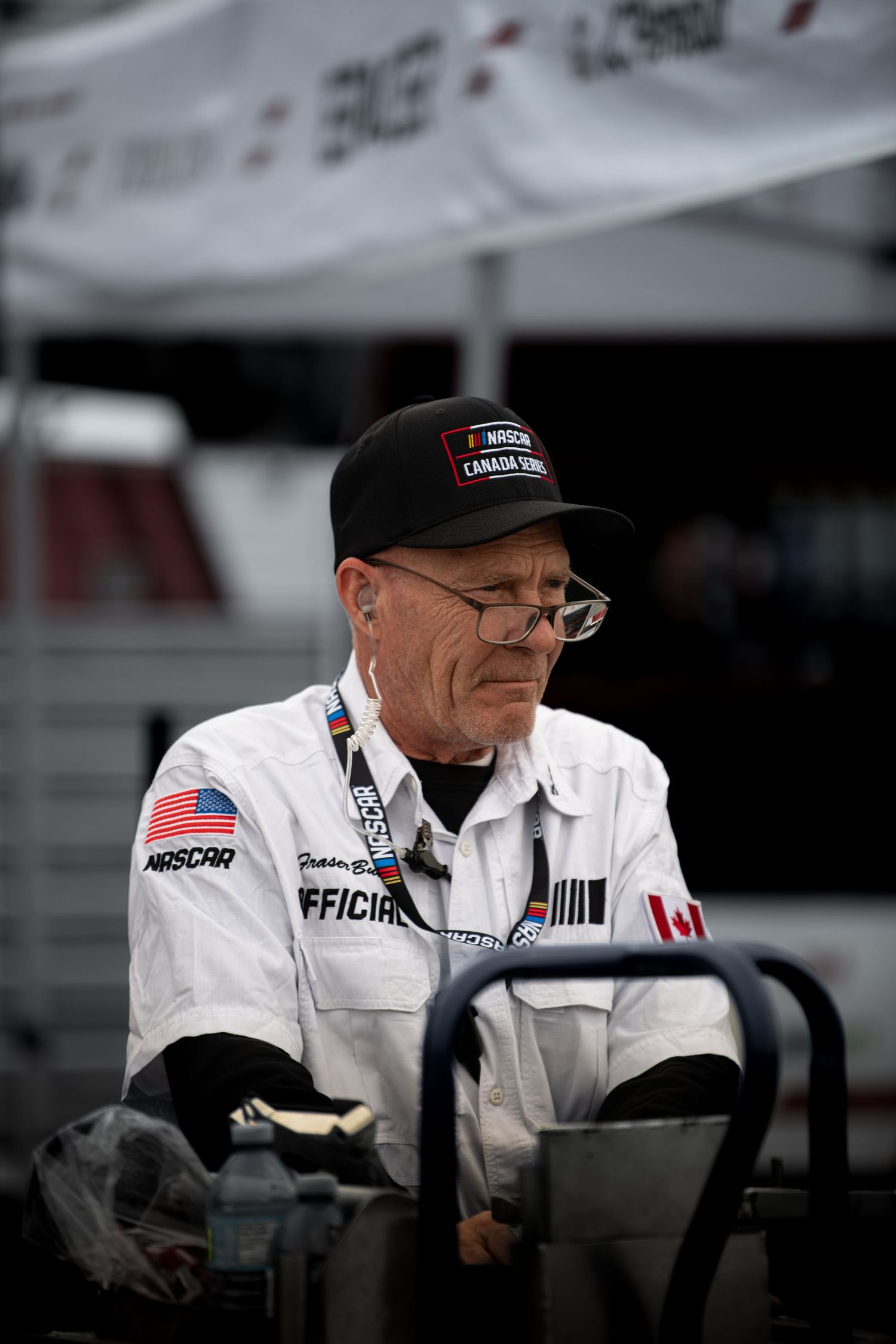 NASCAR official in white uniform and cap operating equipment at a racing event.