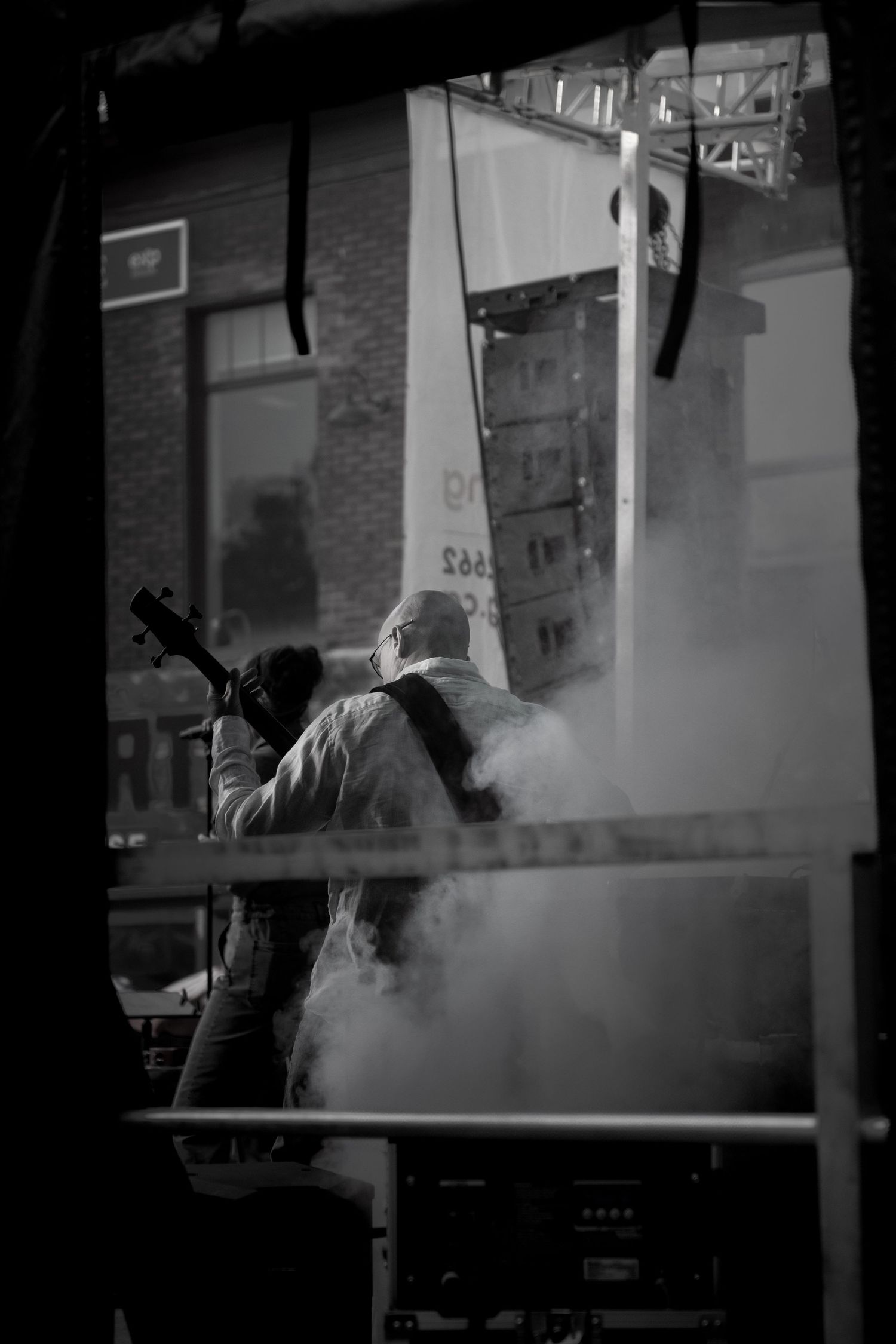Moody black and white photo of a guitar player silhouetted against urban buildings.