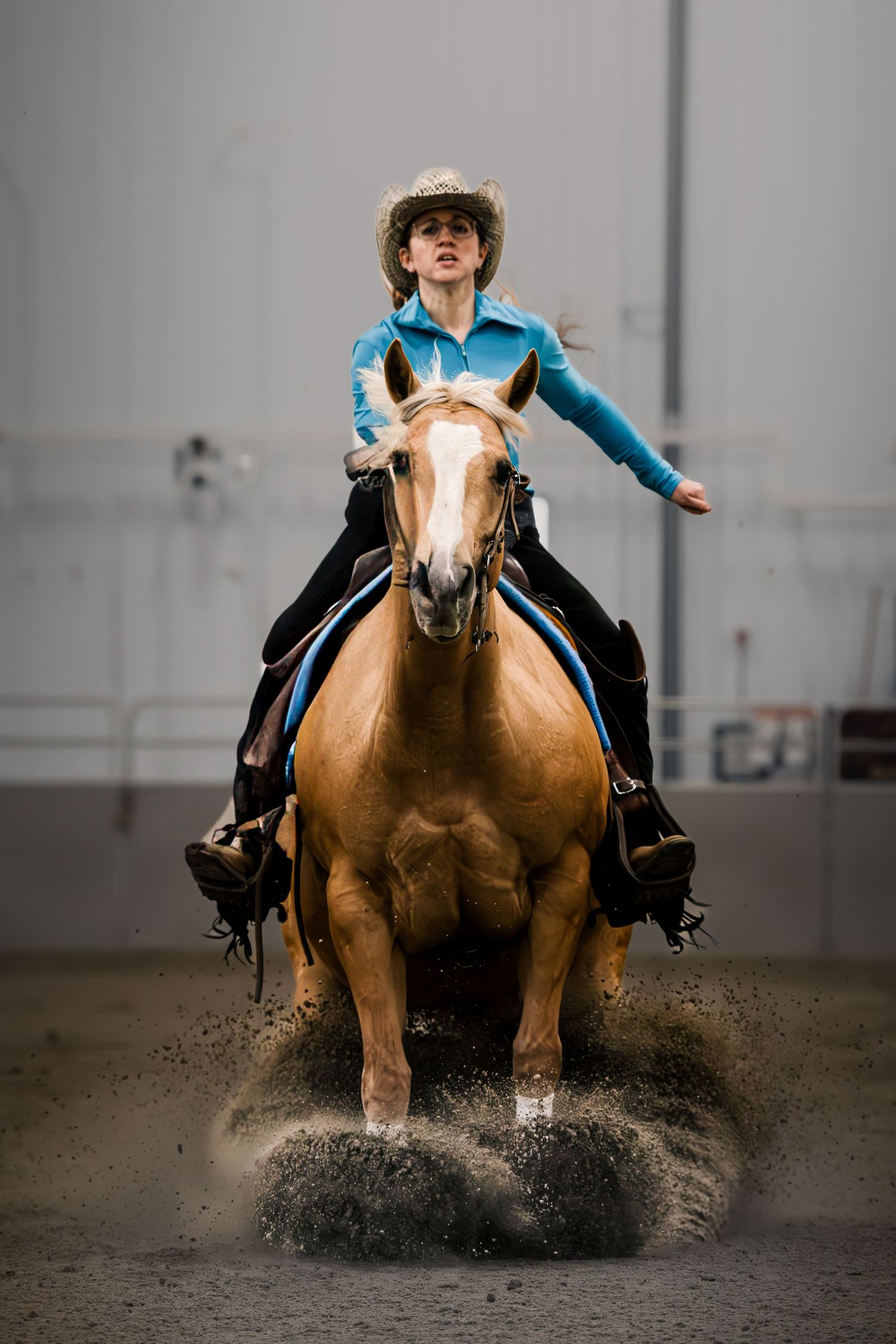 Sequence of a rider performing a sliding stop on a palomino horse in an indoor arena.