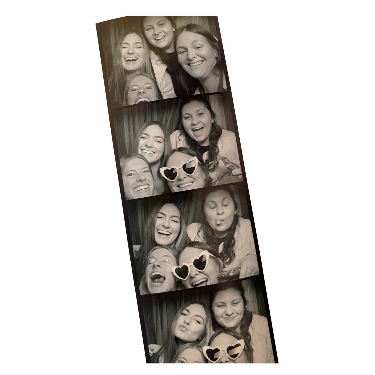 Black and white photo booth strip featuring three young women laughing and posing with heart-shaped sunglasses.