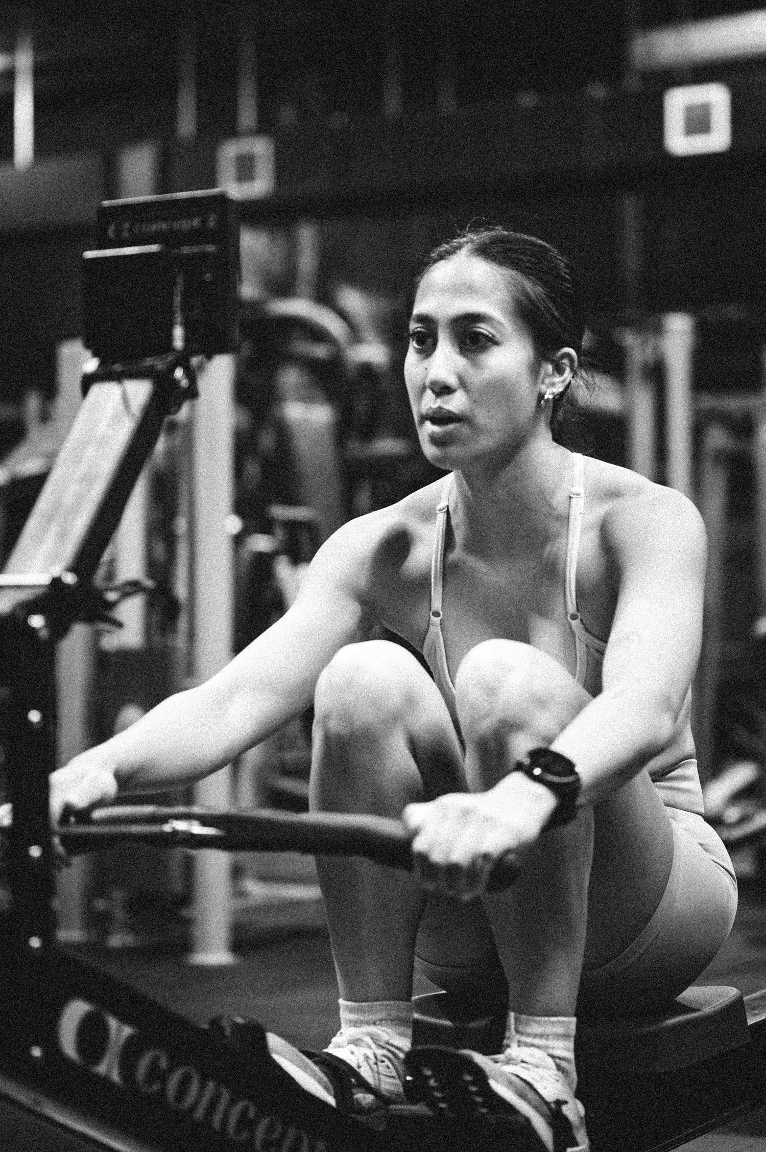 Woman rowing on a Concept2 rowing machine during an intense gym workout session.
