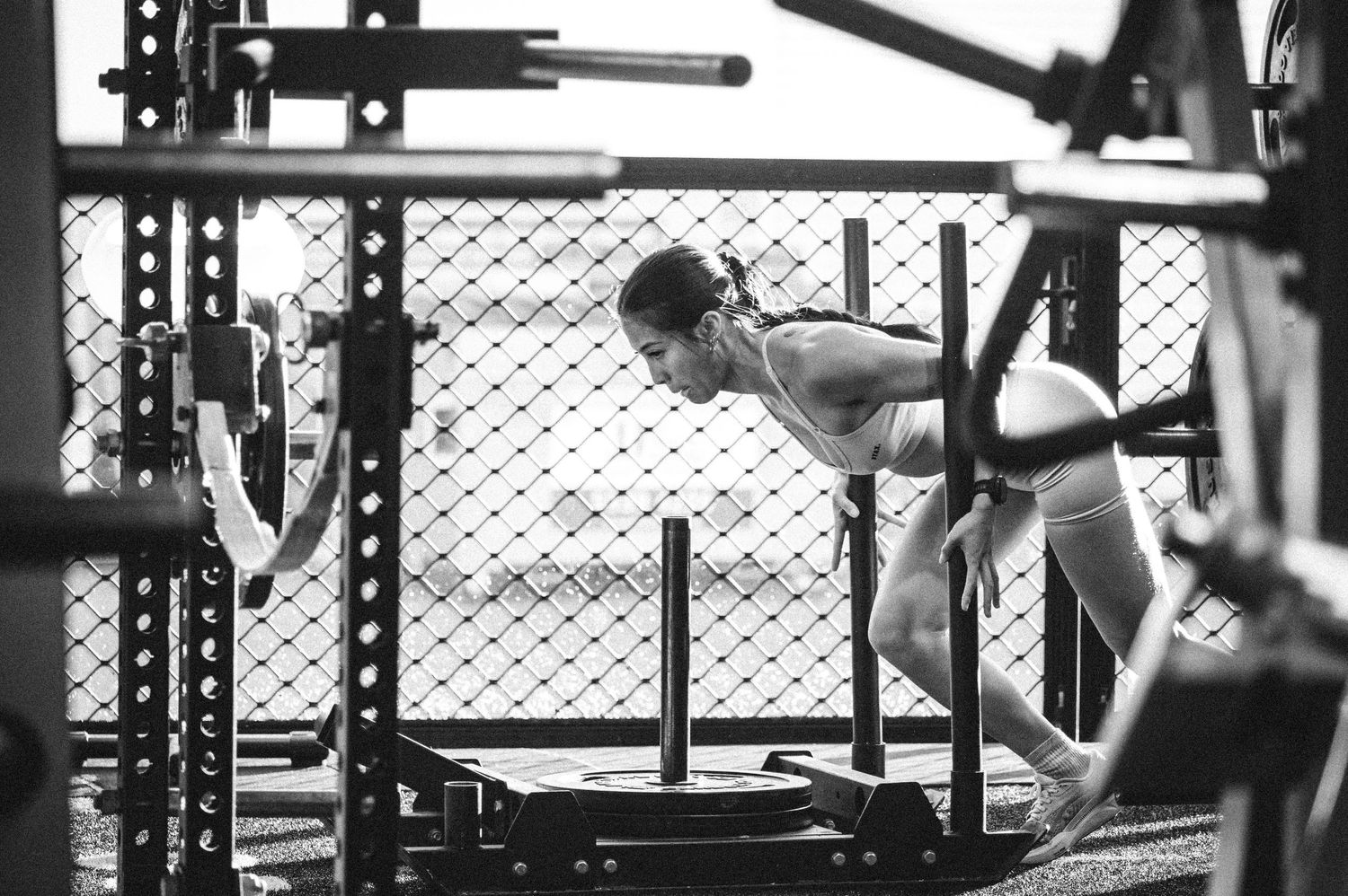 Athletic woman performing a push-up exercise outdoors on a gym rack in black and white.