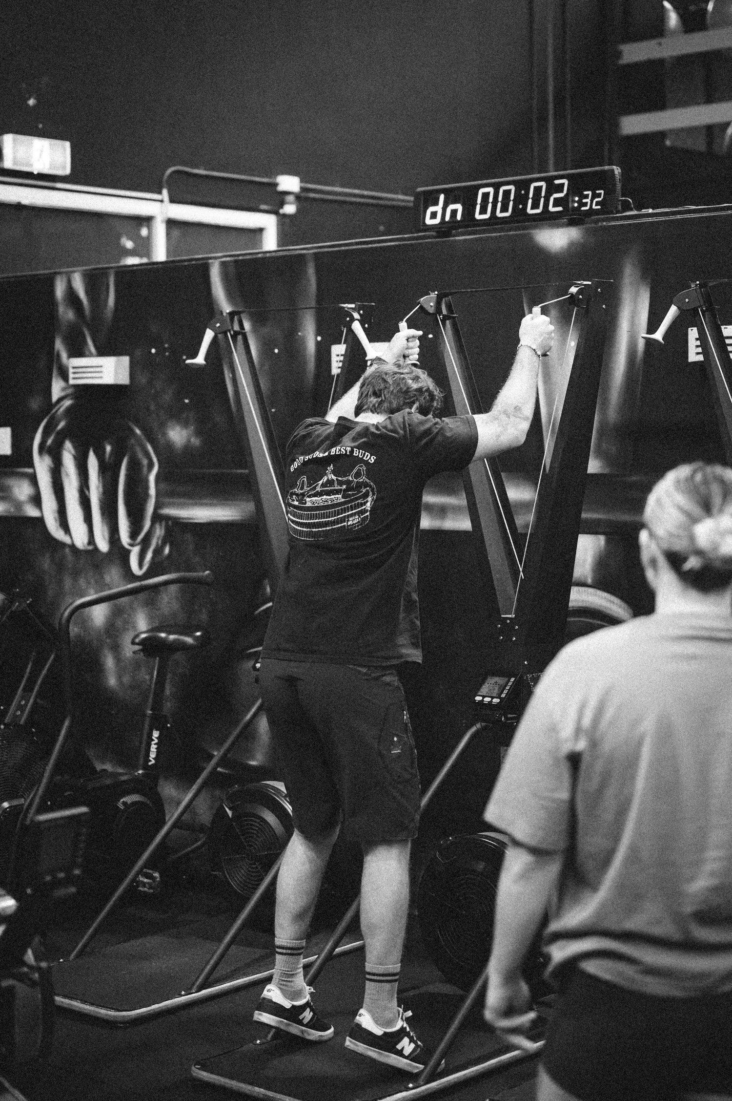 Person using a stair climber machine at a gym with a countdown timer display overhead.