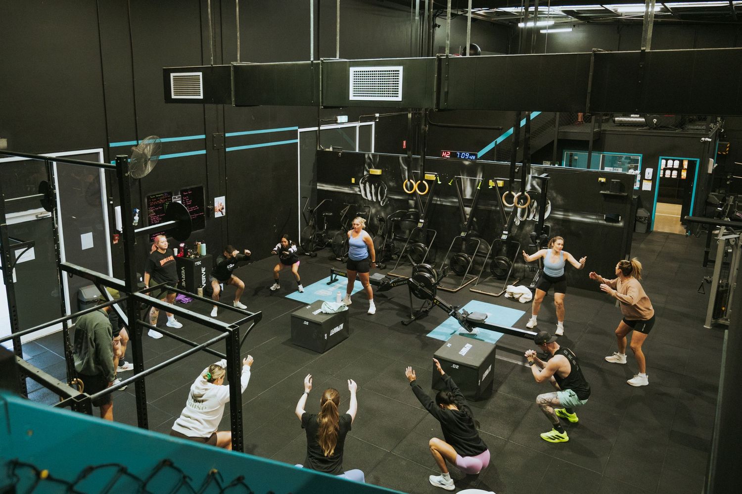 Aerial view of a busy CrossFit gym class with members doing various exercises.