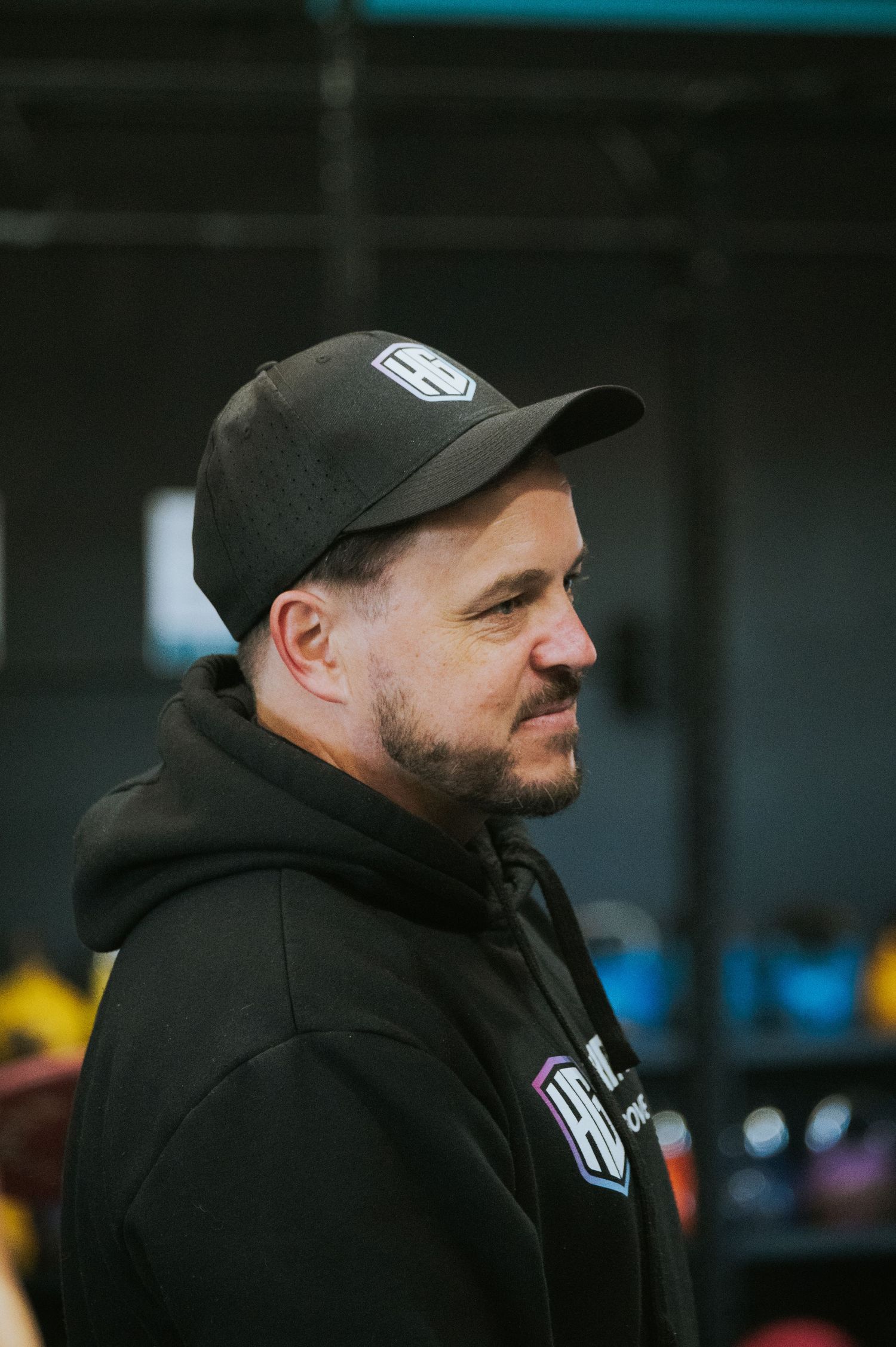 Man wearing a black HG CrossFit hoodie and cap standing in a gym environment.