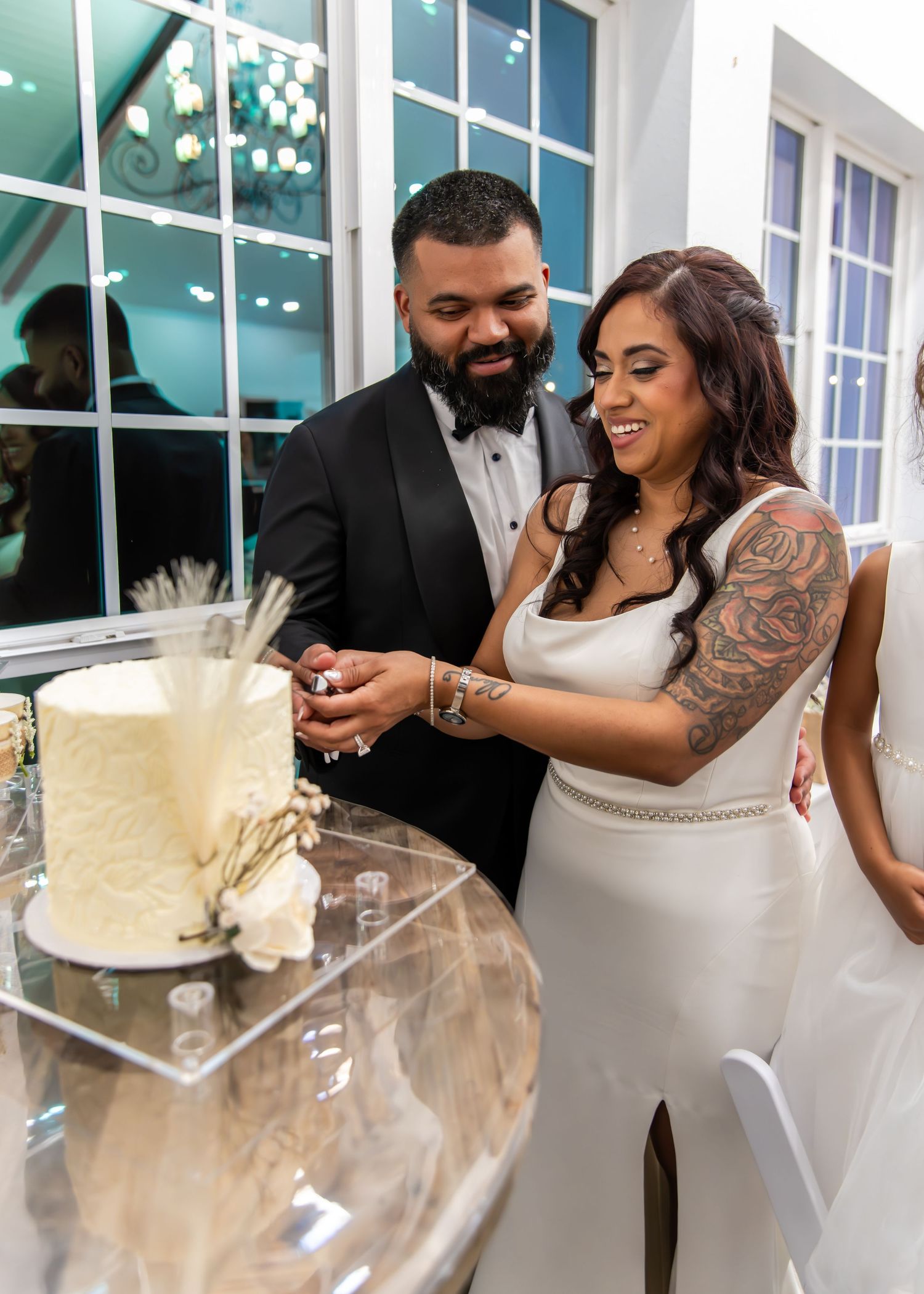 Bride and groom cutting their white wedding cake at an elegant indoor reception venue.