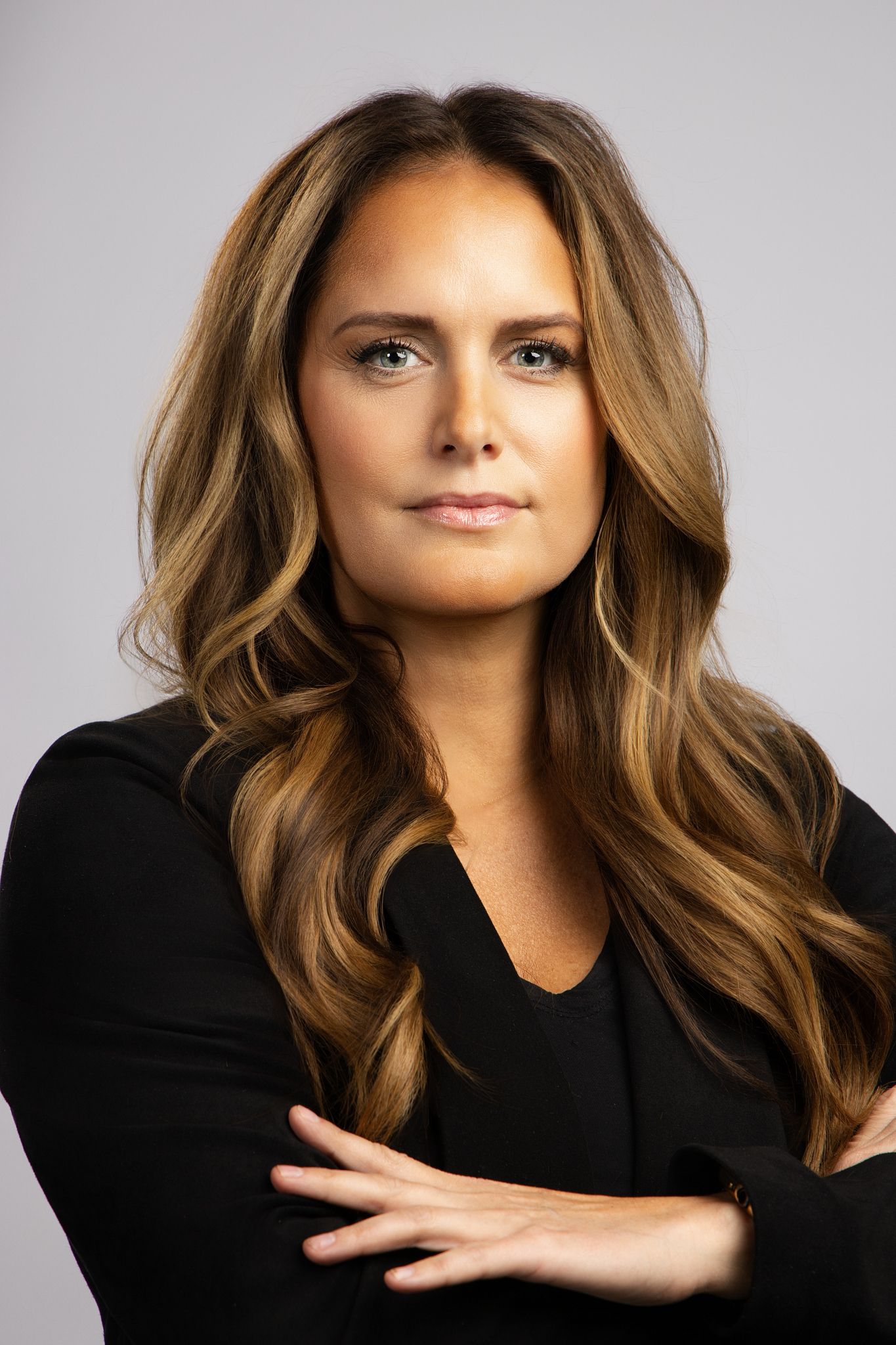 Professional headshot series of a woman with wavy brown hair wearing a black top against a light gray background.