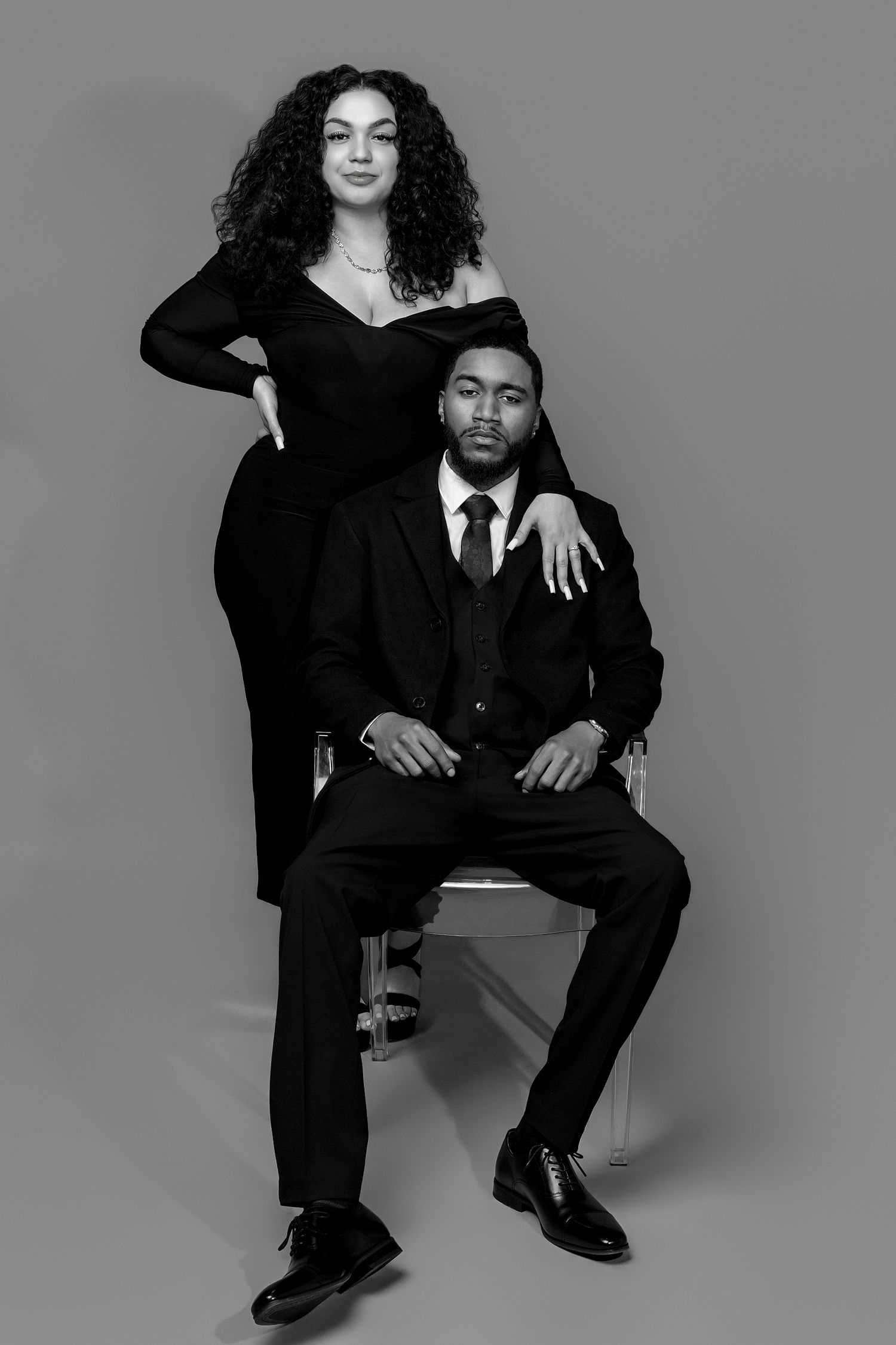Black and white photo series showing a person in formal attire posing against a gray backdrop in various positions.