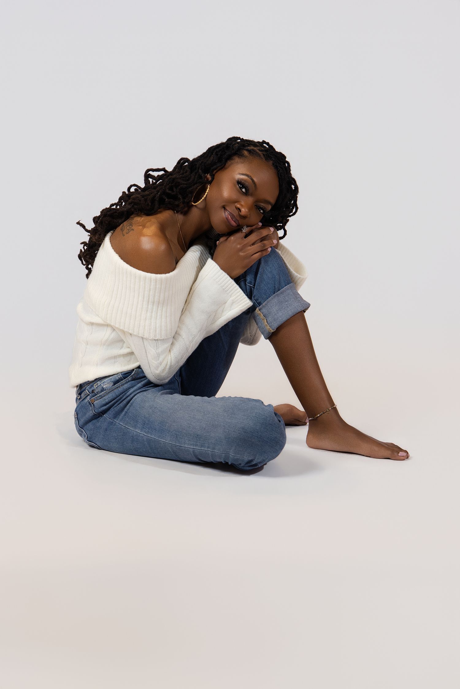 A person in casual denim and white sweater poses artistically on a light background in four sequential shots.