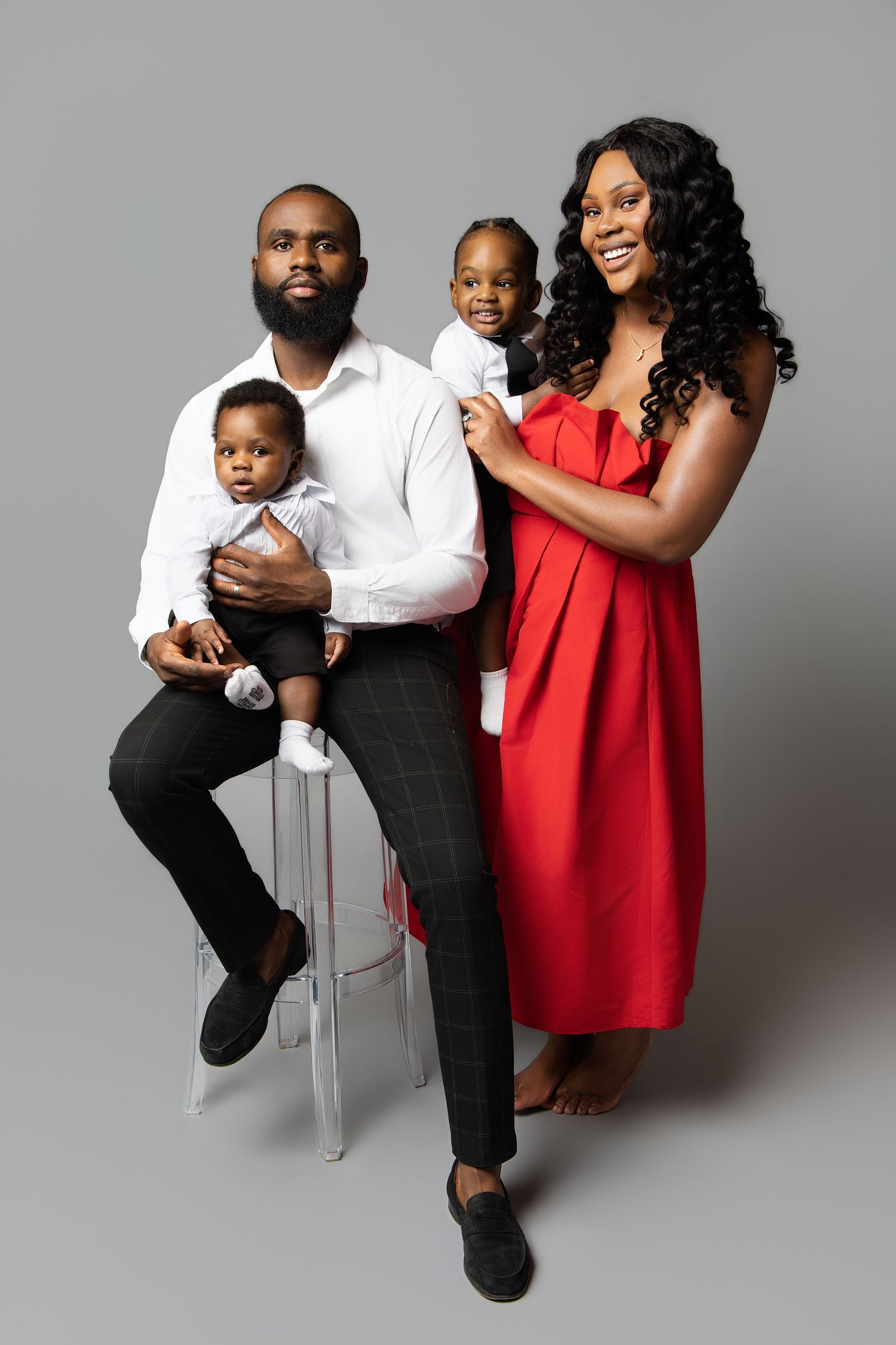 Family portrait series in black, white and red outfits showing loving interactions against a gray studio backdrop.