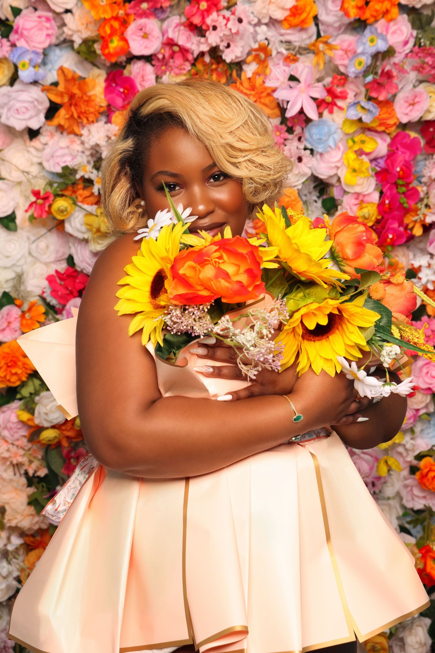 Vibrant portrait with colorful flower wall backdrop and peach pleated dress.