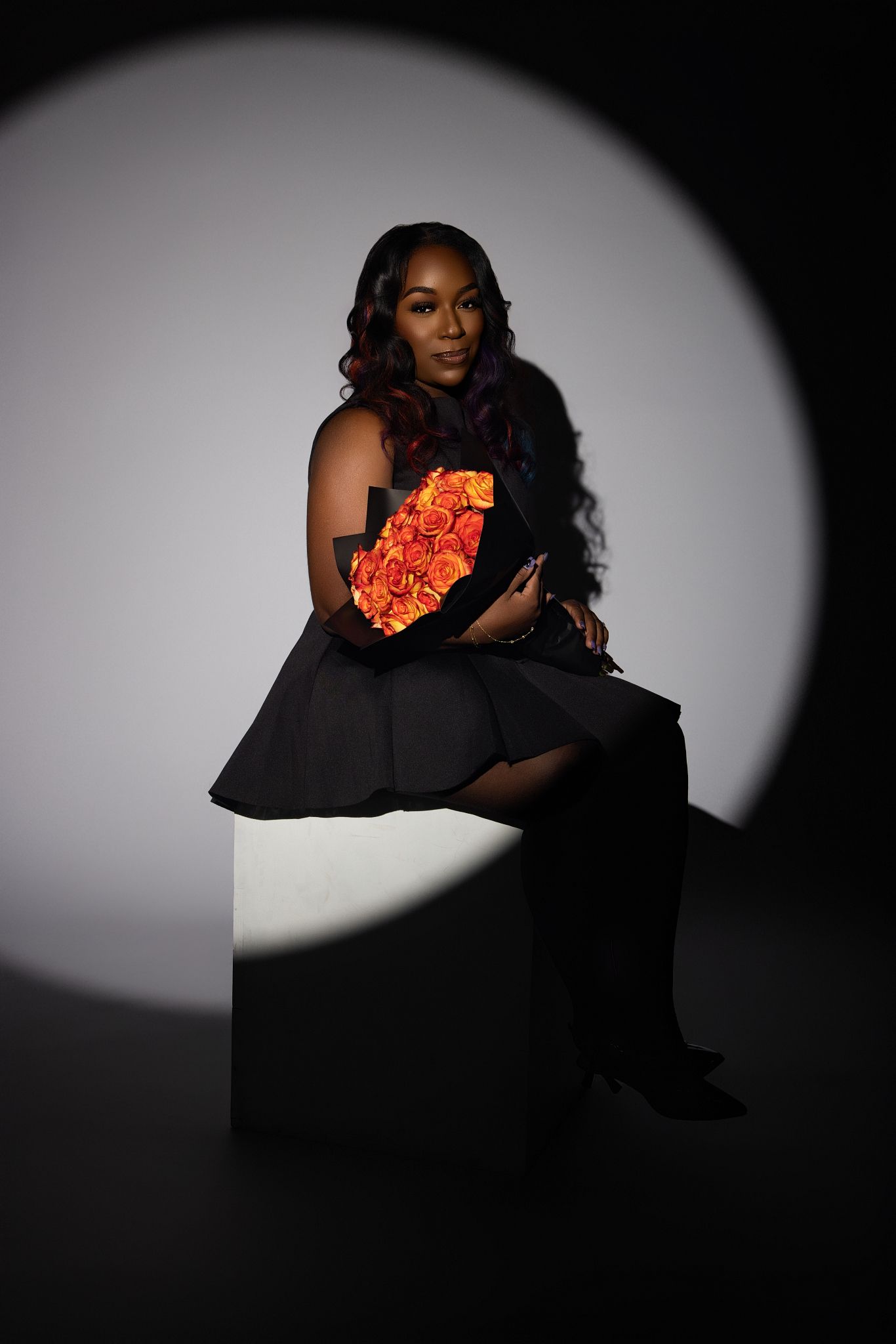 Artistic photo series showing a person in black against a white background holding vibrant orange flowers in dramatic lighting.