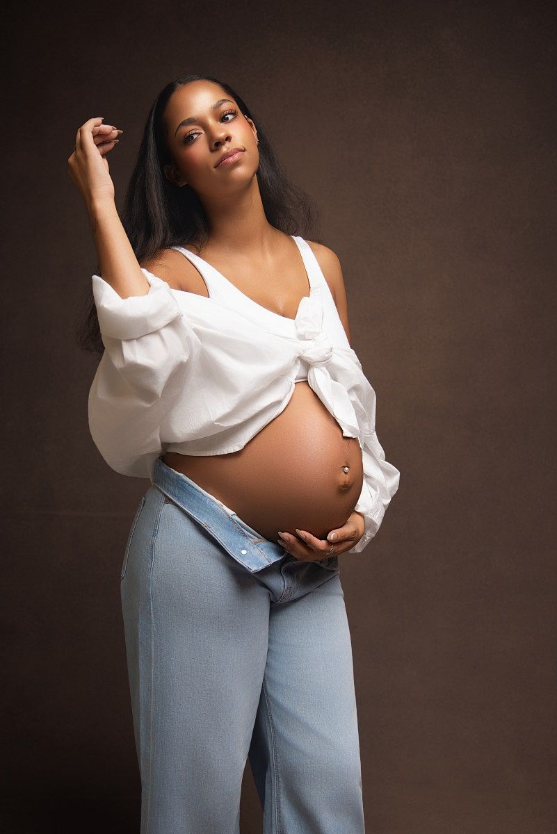 Maternity photo series showing pregnant figure in white blouse and blue pants against dark background.